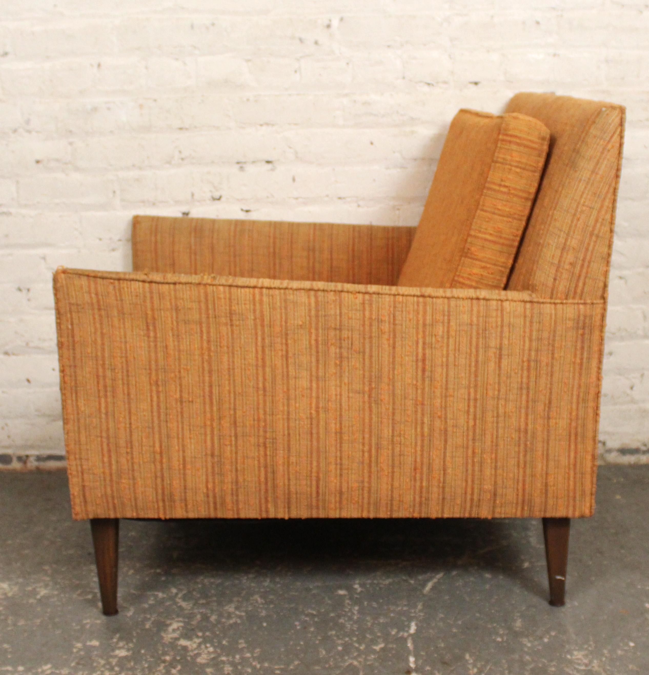 Esta tumbona de fabricación estadounidense evoca el sillón Model 302 de Paul McCobb. El diseño recto del respaldo sigue hasta los brazos en ángulo, y termina con patas cónicas de nogal. 
Por favor, confirma la ubicación con el vendedor NY o NJ