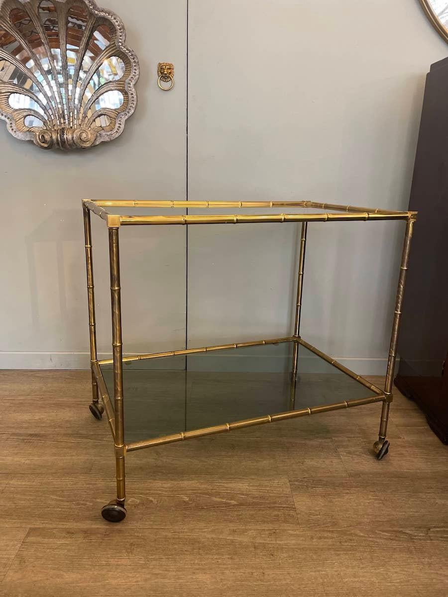 Deco trolley featuring a brass frame with baguès-style details reminiscent of bamboo. The shelves are made of smoked glass.
Dimensions: 72.5 x 48.5 x H 66.5 cm.

Price INCLUDES the costs for any packaging and crates needed to protect the item and