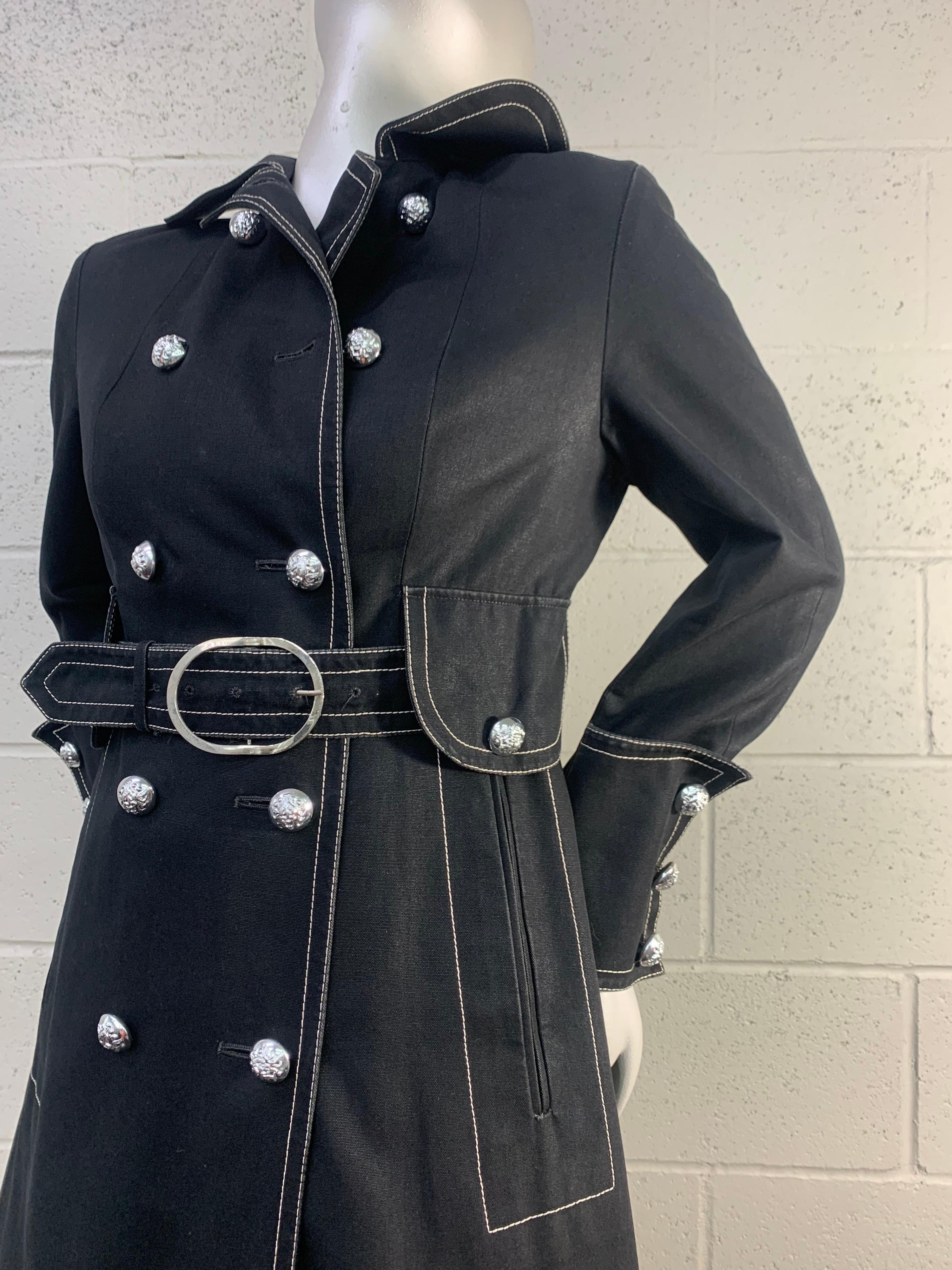 1960 Aquascutum - London black canvas trenchcoat with matching original belt and white topstitching. Silver insignia buttons embellish this smart and functional jacket. Aquascutum was the official maker of rainwear for the Royal Family in Britain
