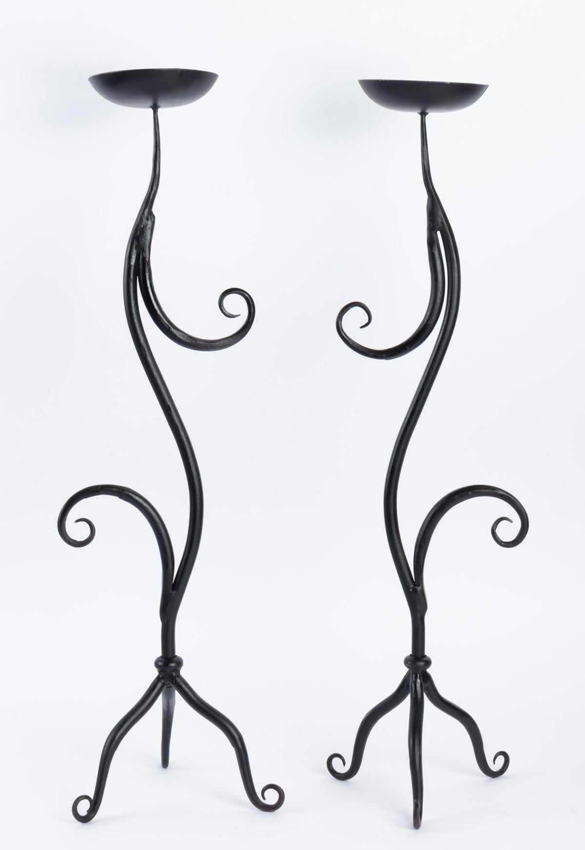 Charming pair of black wrought iron candlesticks, 1960. Ateliers Vallauris.
Each candlestick is composed of a moving rod embellished with two arms forming loops resting on a tripod ending in coils. On the upper part a large cup receives