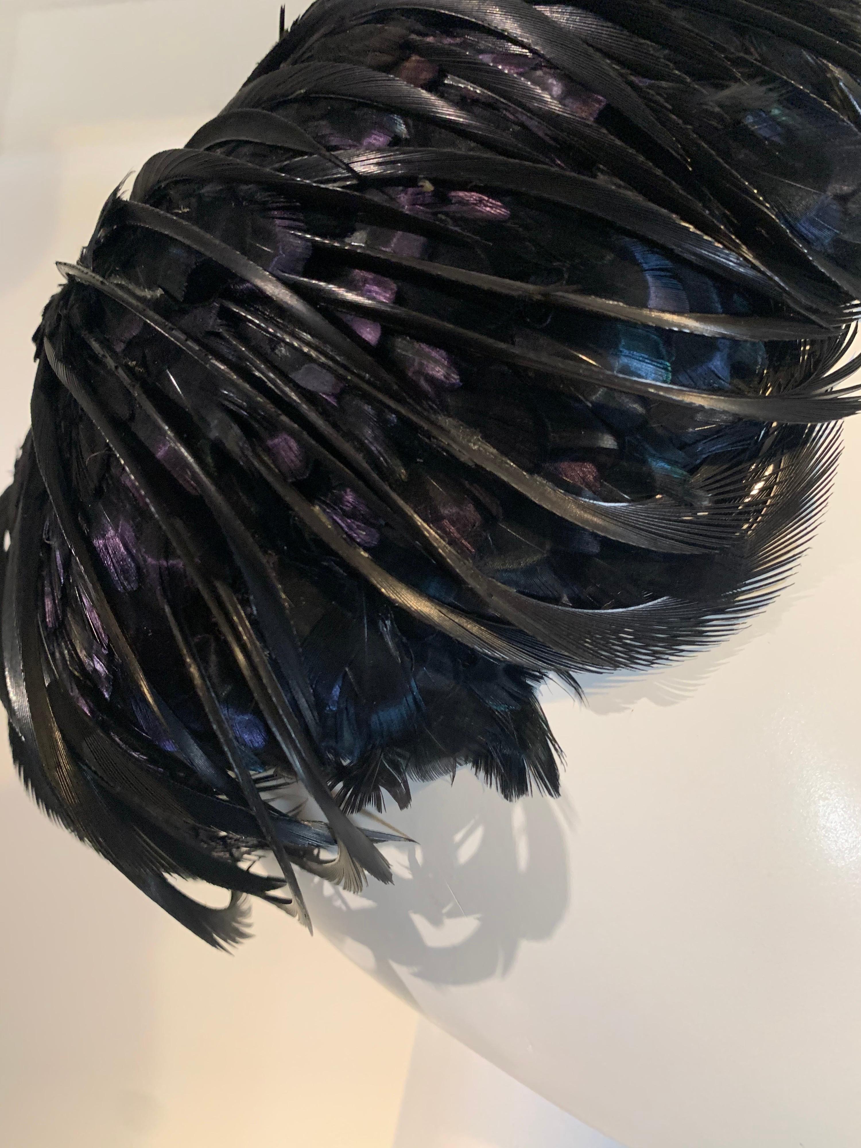 A gorgeous 1960s Christian Dior hat by Marc Bohan: A structured turban-style cocktail hat covered in iridescent blue pheasant feathers is enhanced by crisp black feathers that appear as wisps of hair. One size. 
