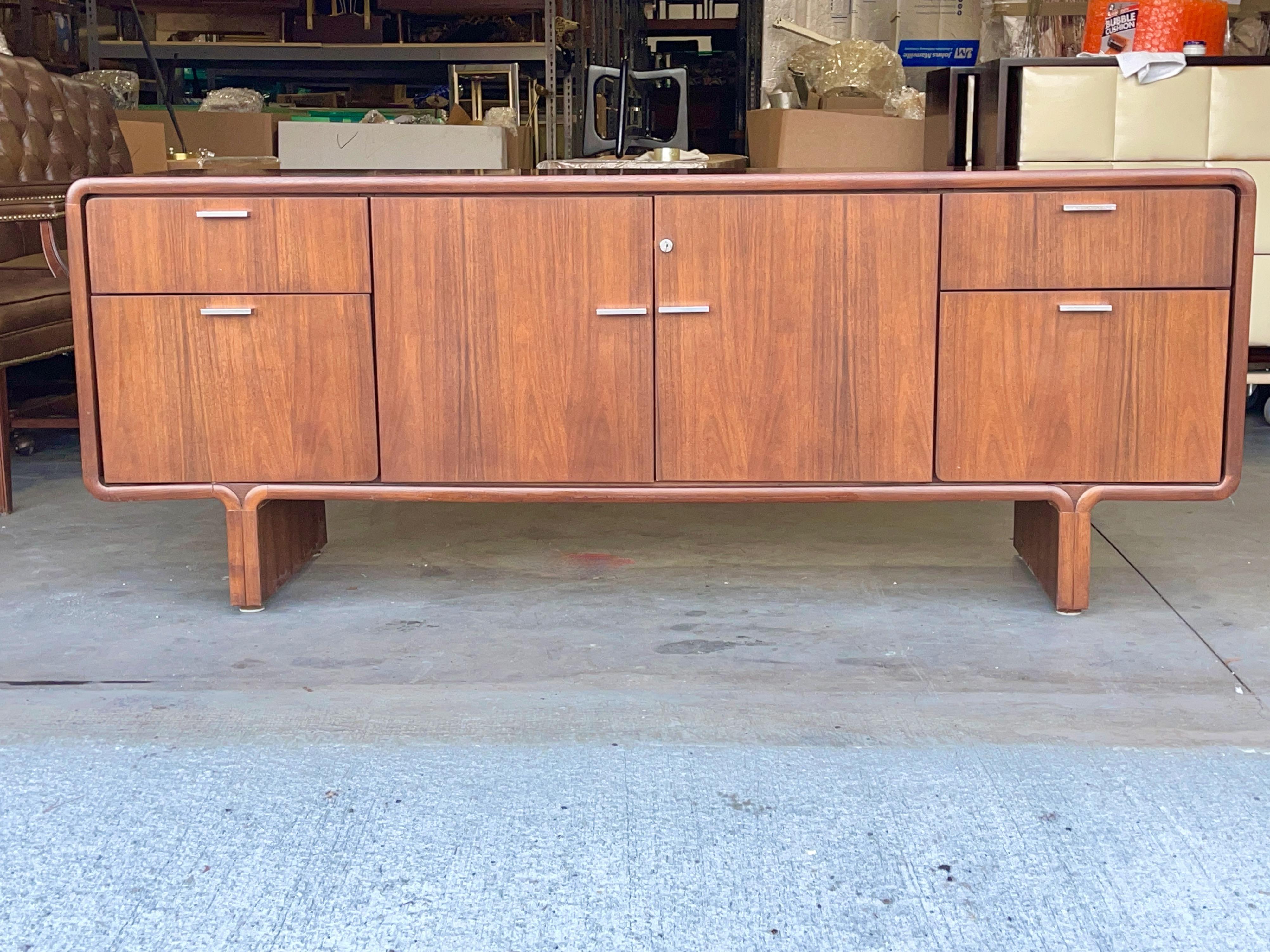 Montreal modern walnut credenza with space age styling exemplified in the top and bottom waterfall edges of the long slender case appearing to float on two eight inch legs.
Finished on backside so can float in the room and be viewed from all