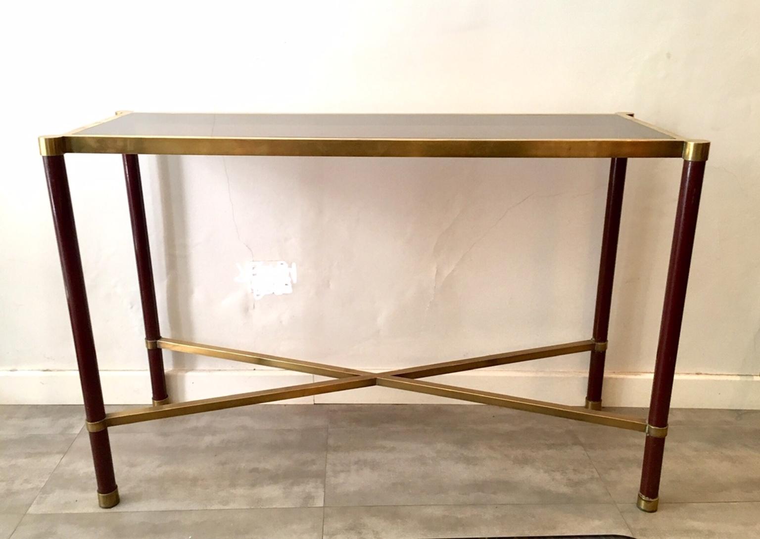 Guy Lefevre design console in lacquered metal in a maroon color with some parts in gold brass, the lid is smoked glass and the bottom in the form of x.