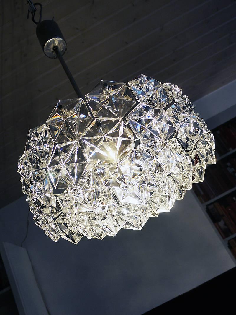 Elegant four-tier starburst chandelier with sculptural faceted crystals on a round chromed brass frame. Has 7 sockets. In very good condition. Chandelier illuminates beautifully and offers a lot of light. Gem from the time. With this light you make