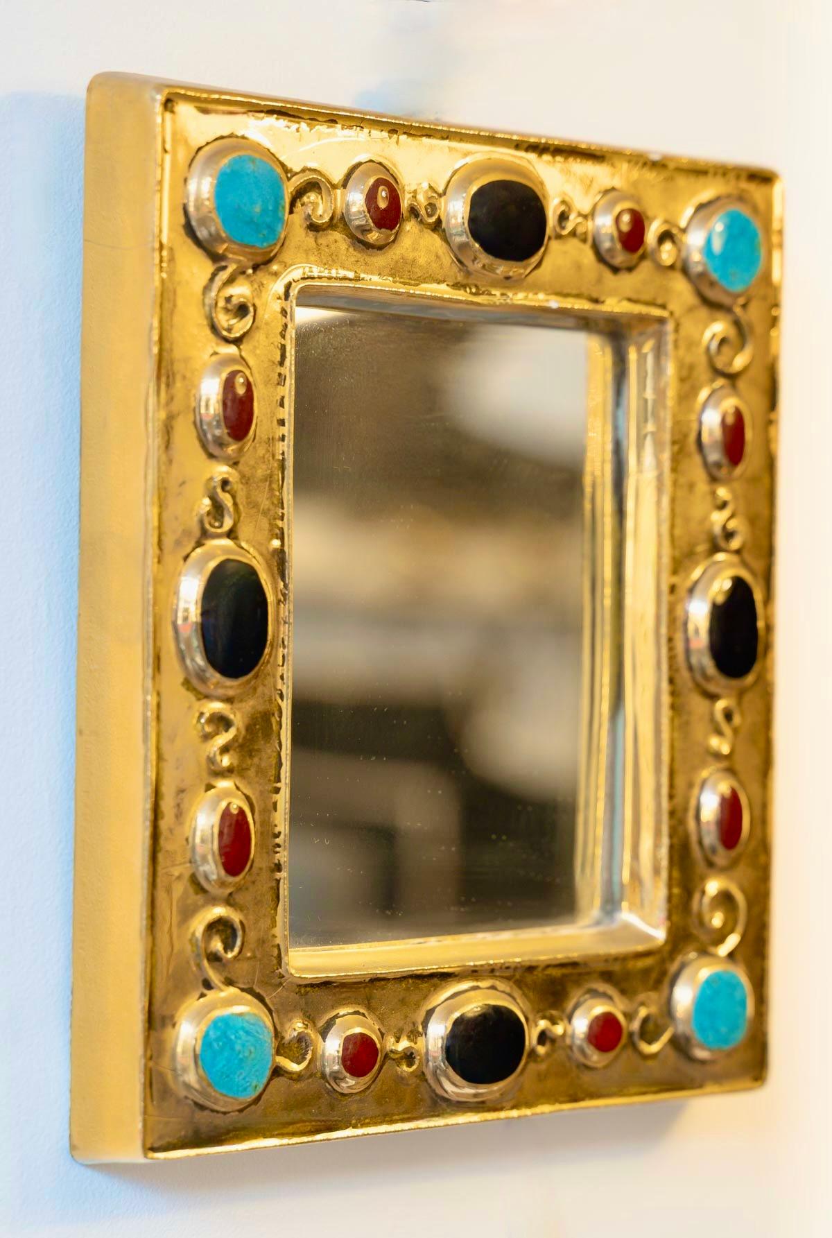  
Petit miroir rectangulaire, émail doré, à décor incrusté imitant des bijoux de couleur vert émeraude, noir et rubis, signé.
Signé F. Lembo avec signature incisée au dos.  

Originaire de Vallauris, François Lembo a commencé sa carrière de potier