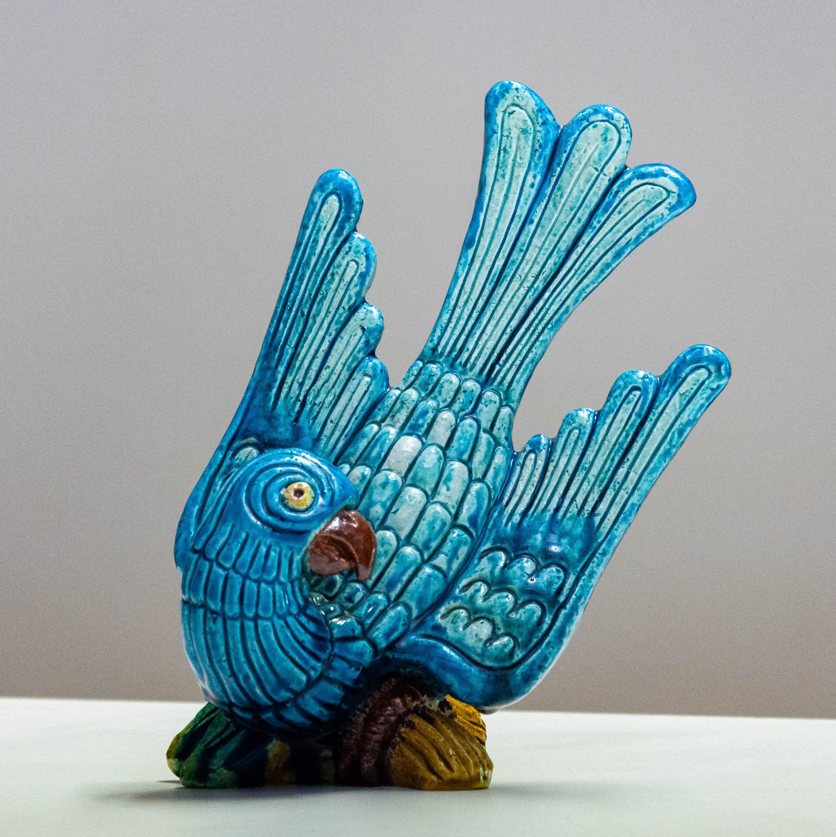 This vibrant ceramic sculpture depicts a stylized blue parrot with exaggerated tail feathers and finely detailed plumage. Designed by renowned Swedish designer Gunnar Nylund for Rörstrand, one of Sweden’s most prestigious porcelain manufacturers,