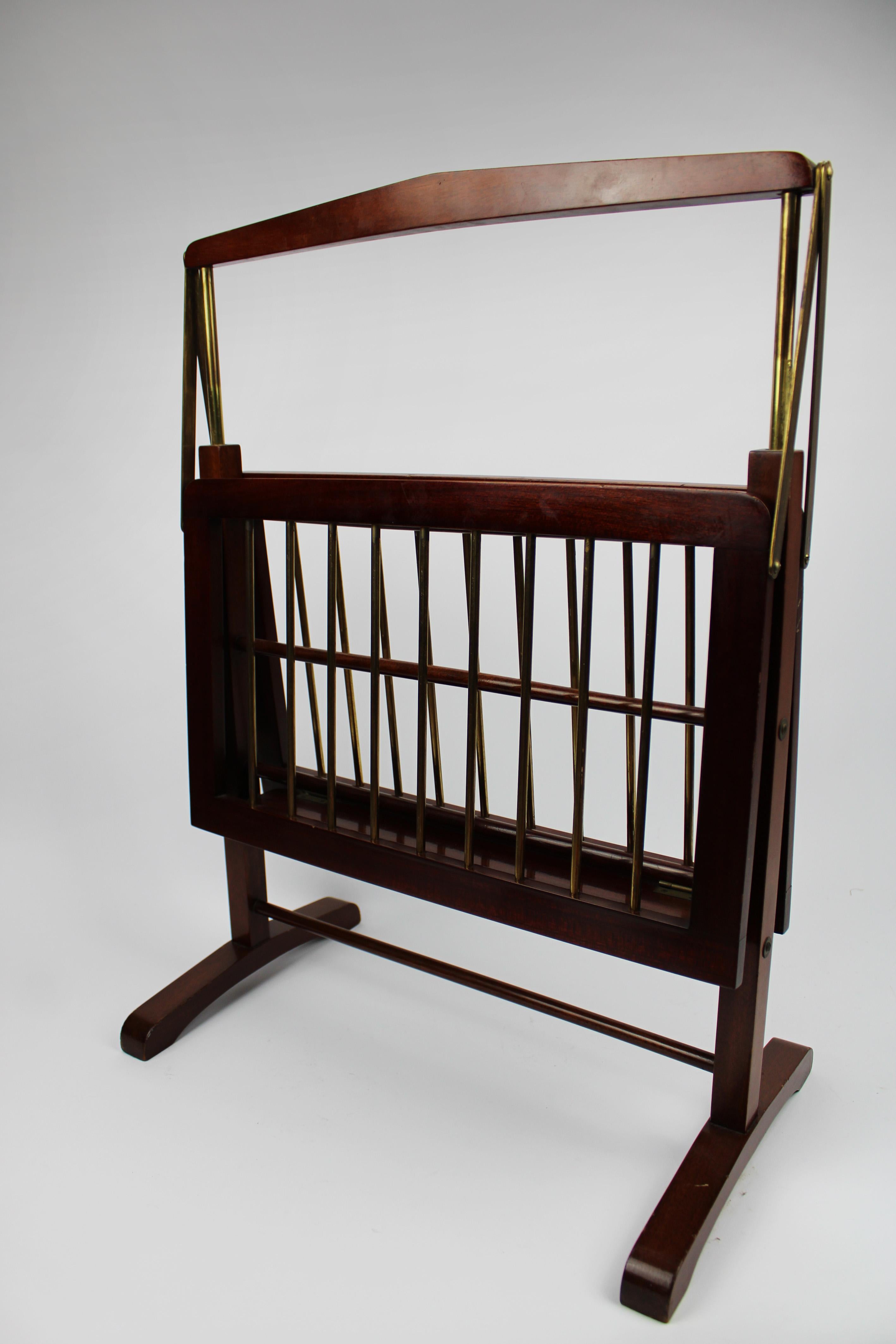 Introducing a stylish magazine rack from 1960, designed by Cesare Lacca and crafted in Italy. Made from elegant walnut and brass, this piece exemplifies mid-century modern design. Notably, the storage rack is collapsible, offering both functionality