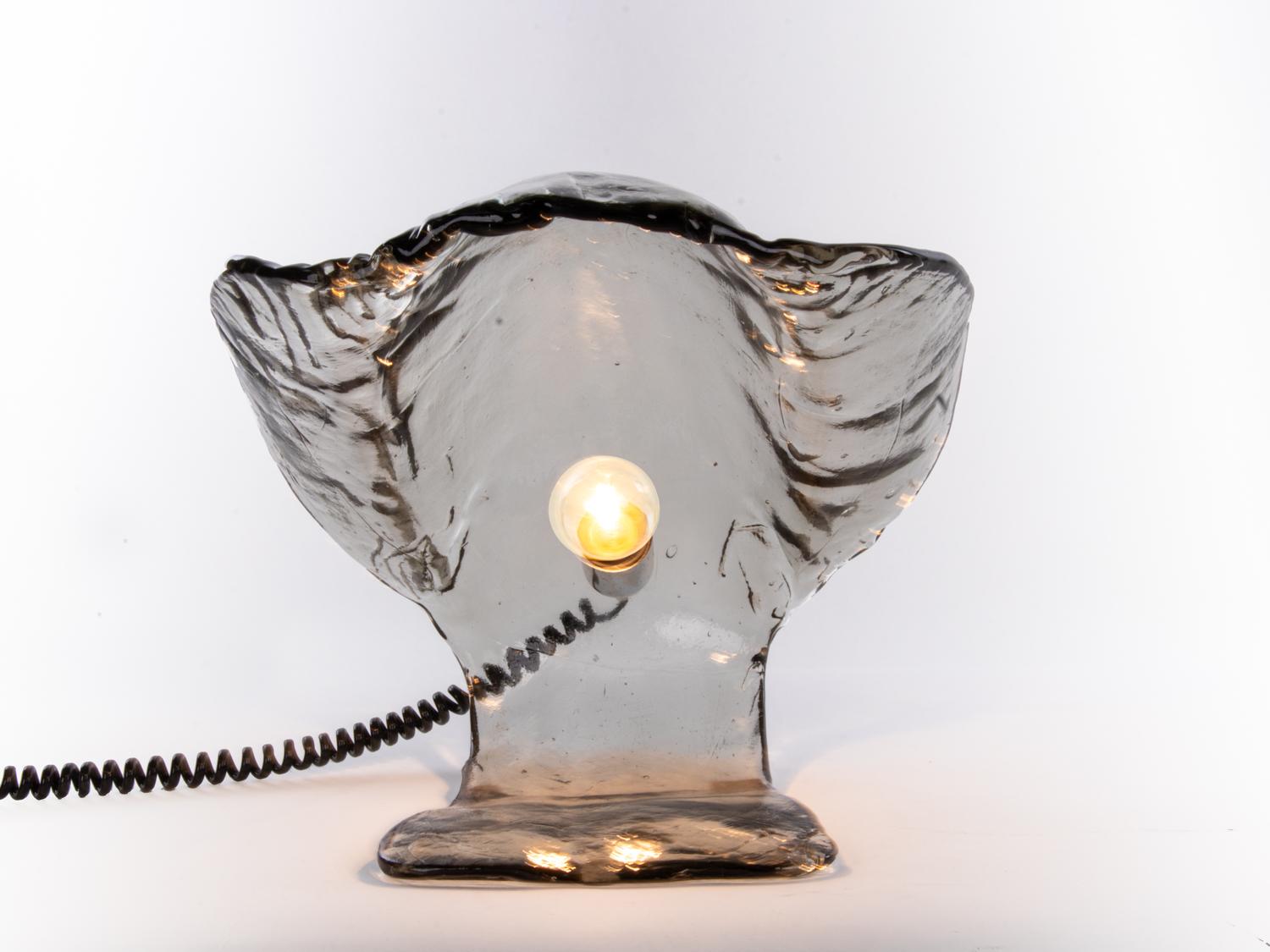 Oyster shaped table lamp made of thick hand blown smoked Murano glass. 
This imposing piece creates an elegant atmosphere around. Manufactured by Mazzega, Italy in the 1960s. 

Design: Carlo Nason attr. 
Maker: Mazzega. 
Lighting: takes one large