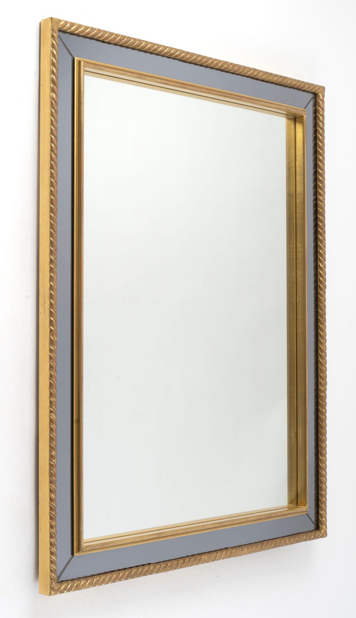 Composé d'un cadre en bois torsadé à la patine dorée.
À l'intérieur, un autre cadre doré sépare le miroir central de couleur neutre du miroir en verre fumé formant le cadre