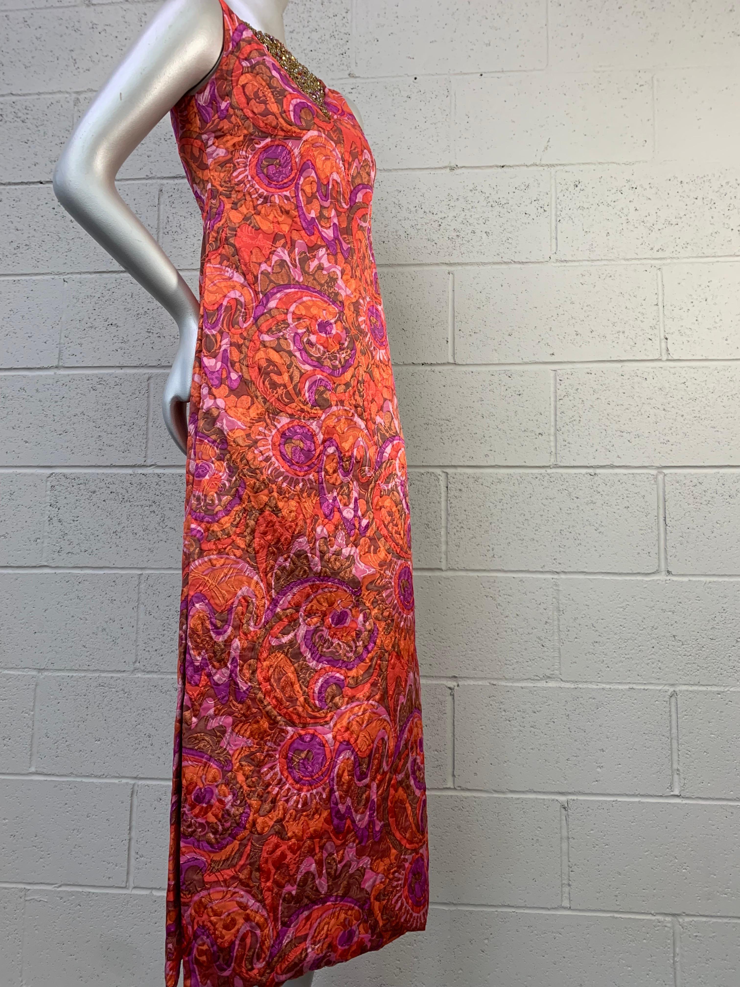 A beautiful 1960s Julius Garfinkle Mod silk lame brocade sleeveless column gown with side slit in a psychedelic print over floral/paisley pattern of orange, purple and lavender palette. Neckline features a heavily beaded and rhinestoned Mughal-style