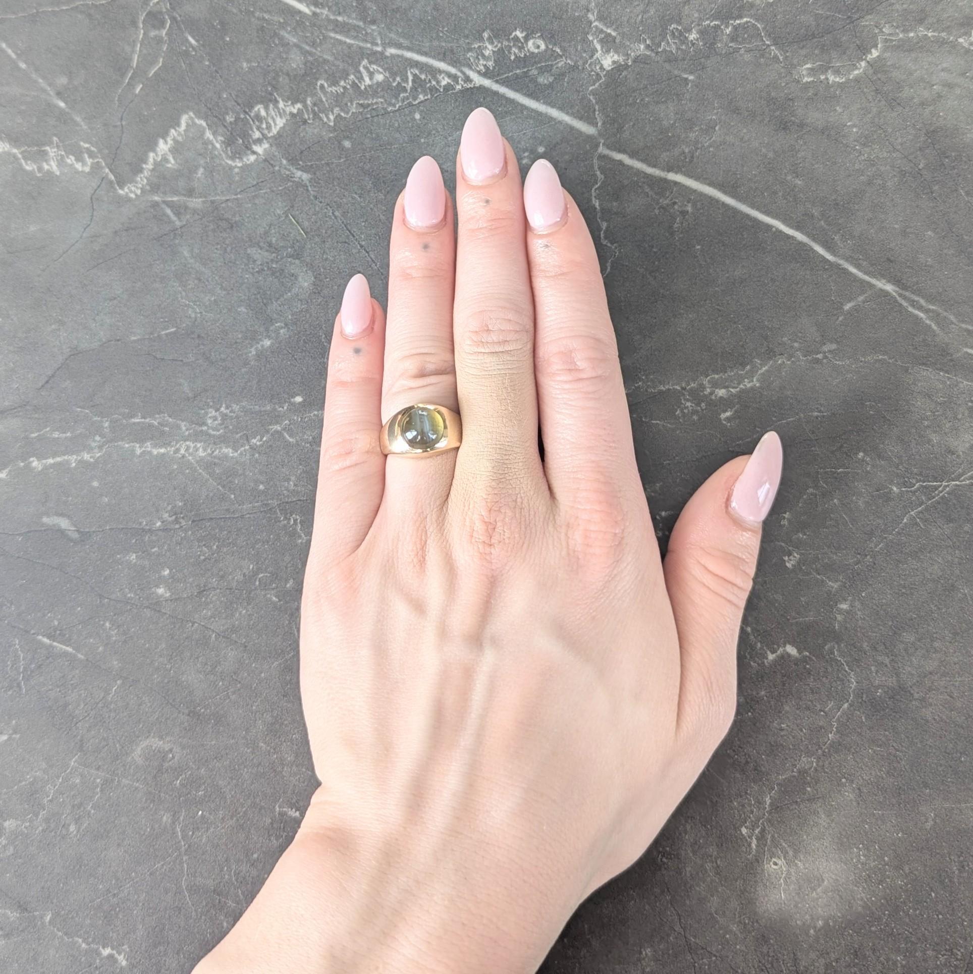 Centering a round shaped cat's eye chrysoberyl cabochon measuring 9.0 x 9.0 mm round
Natural transparent greenish yellow with strong linear white 'milk and honey' chatoyancy
Flush set with a slightly bombé shaped surround
Completed by high polish