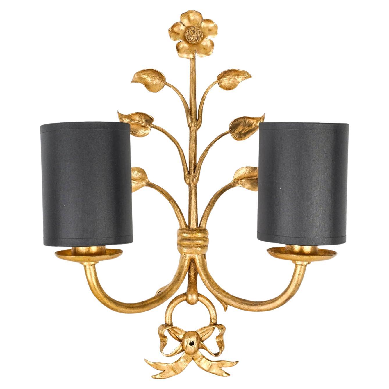 Composed of a central stem adorned with a flower at the top and branches embellished with leaves on either side of the sconce.
Two arms of light rise from the lower part of the sconce and are clad with cylindrical black cotton shades highlighted by