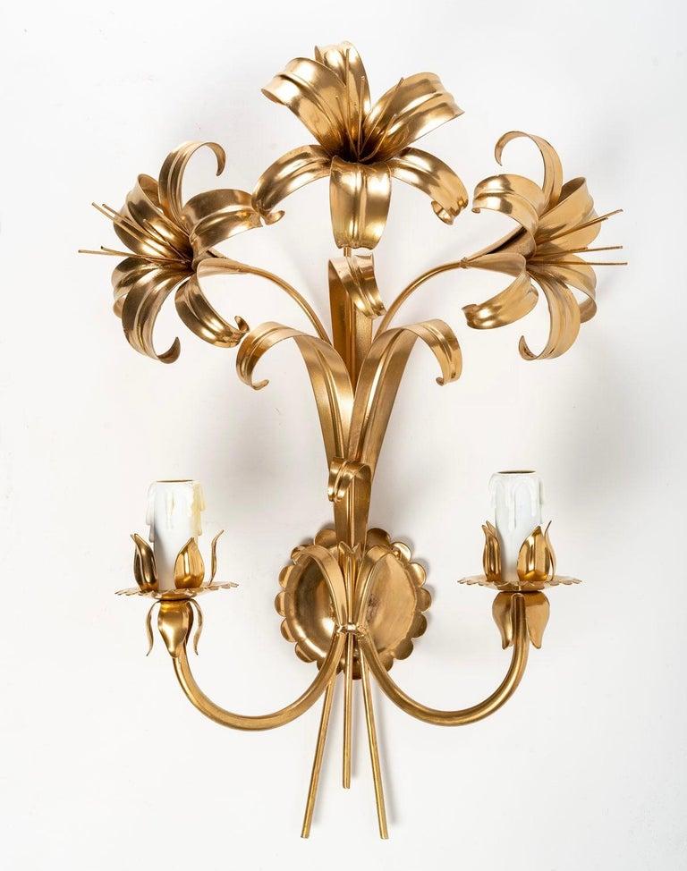 Composed of a round wall plaque with a serrated edge on which rests a bouquet of fleur-de-lis and foliage embellished in the lower part of two arms of light going up distributed on each side of the sconce.
They are dressed in candlelight and