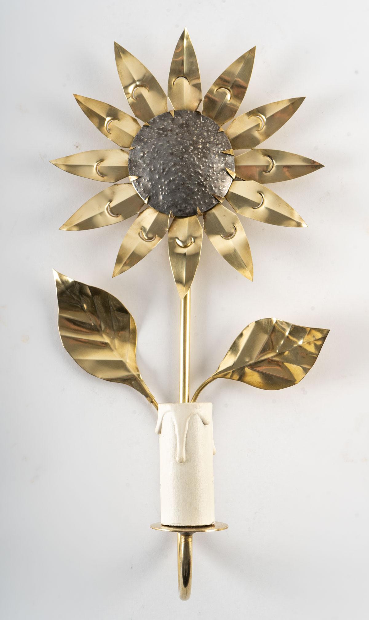 
Composed of a thin gilded brass stem decorated on the upper part with a sunflower, the petals are in gilded brass.
On the lower part, the stem rises towards the front of the sconce, it is underlined by two golden brass leaves.
It is dressed with a