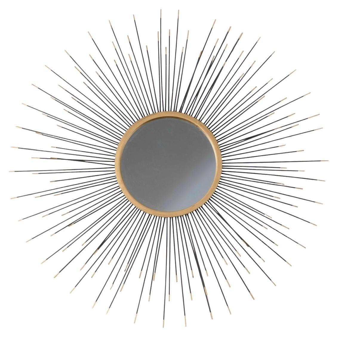 Large pair of witch mirrors.

Composed of a central round mirror highlighted by a wrought iron frame with a golden patina, around which radiate  thin, long round rods simulating the rays of the sun at different heights, made of black wrought iron