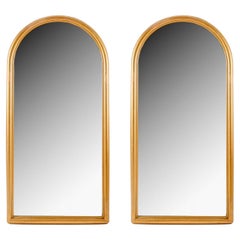 1960 Paire de miroirs en bois mouluré et doré inspirés d'une ogive romane.