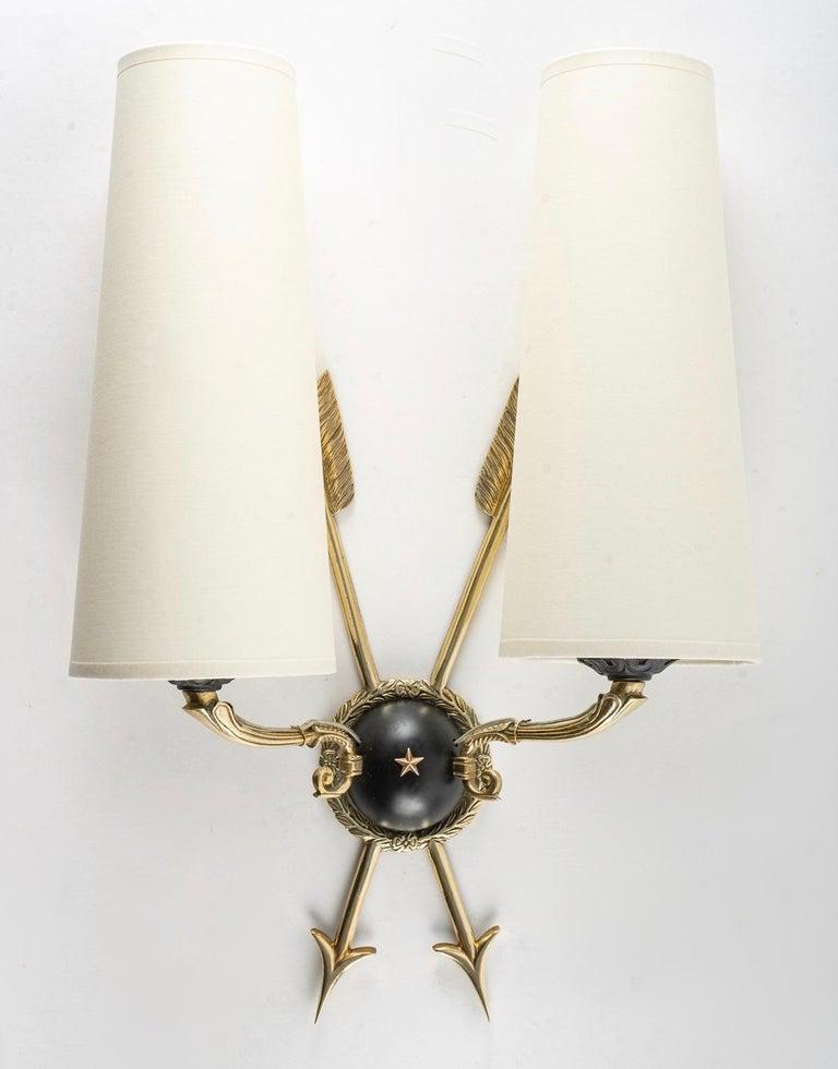 Pair of neoclassical Maison Roche wall lights from the 1960s.

Composed of a round-bottom wall plaque in black lacquer, decorated around the perimeter with a wreath of leaves and a star placed in the center and adorned with two crossed arrows in
