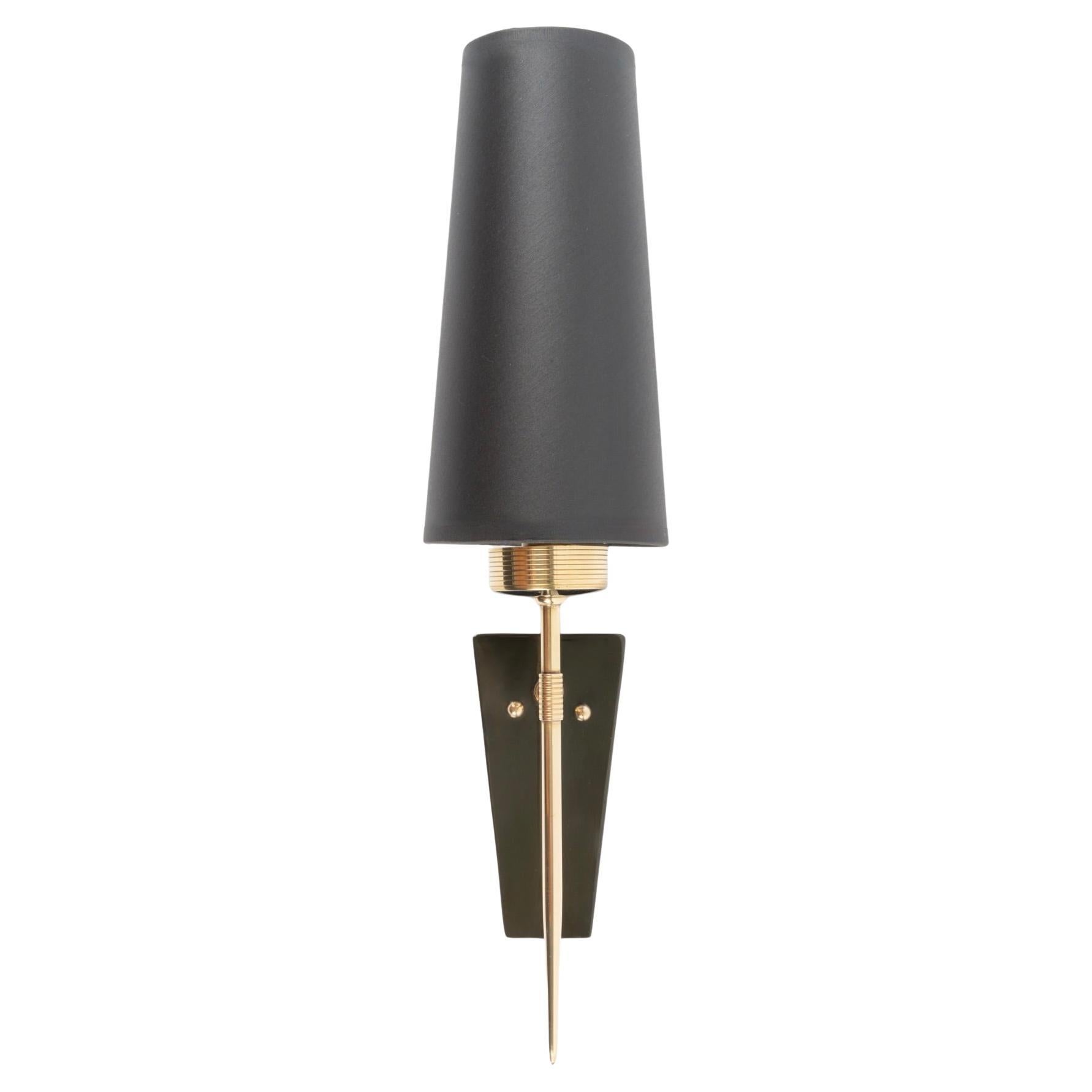 Composed of a round wall bracket in gold-plated brass supporting a black trapezoidal plate in Perplex, embellished with small gold-plated brass balls. 
At the front, a small arm supports a pointed golden brass rod at the bottom. 
At the top, the