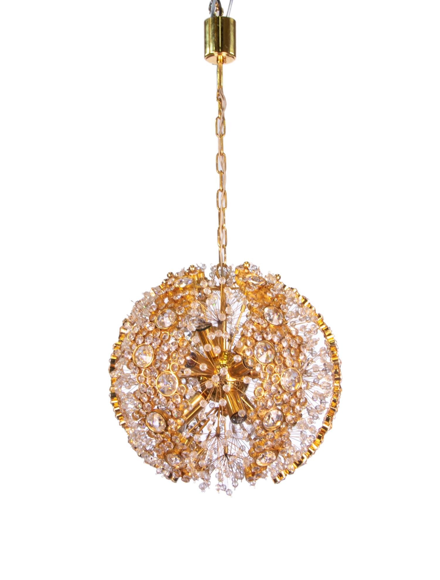 Enchanting sunburst ball chandelier with sparkling stars for infinity. Swarovski crystals placed on gold-plated sun rays explode between pulsating sun discs studded with crystals of different sizes mounted on a 14-karat gold-plated brass frame. Has