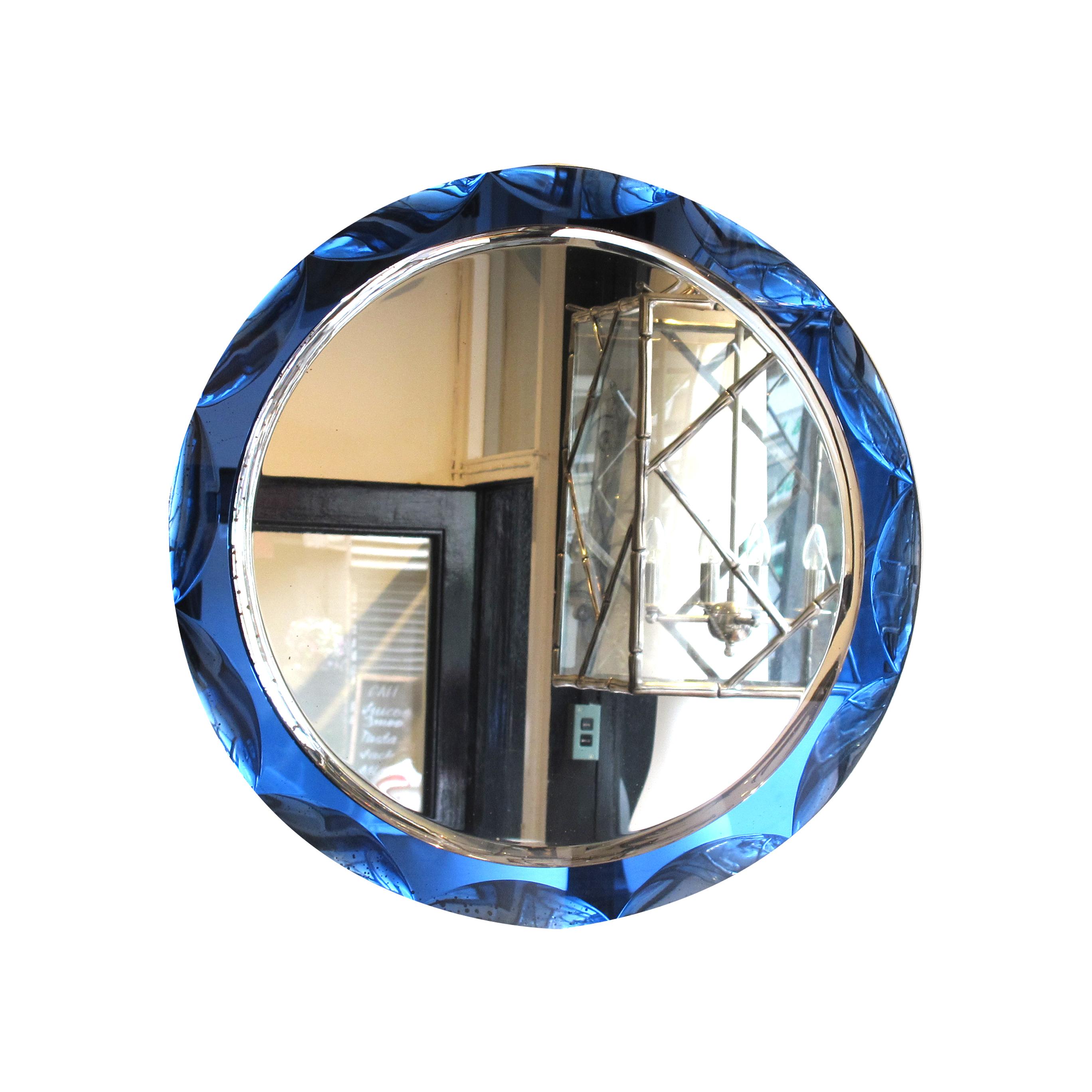 Stunning 1960s round mirror with semi-circles and a deep blue mirrored frame. The mirror features a circular shape with a large, bevelled edge that gives it a three-dimensional appearance. The outer frame is made of deep blue mirrored glass, adding
