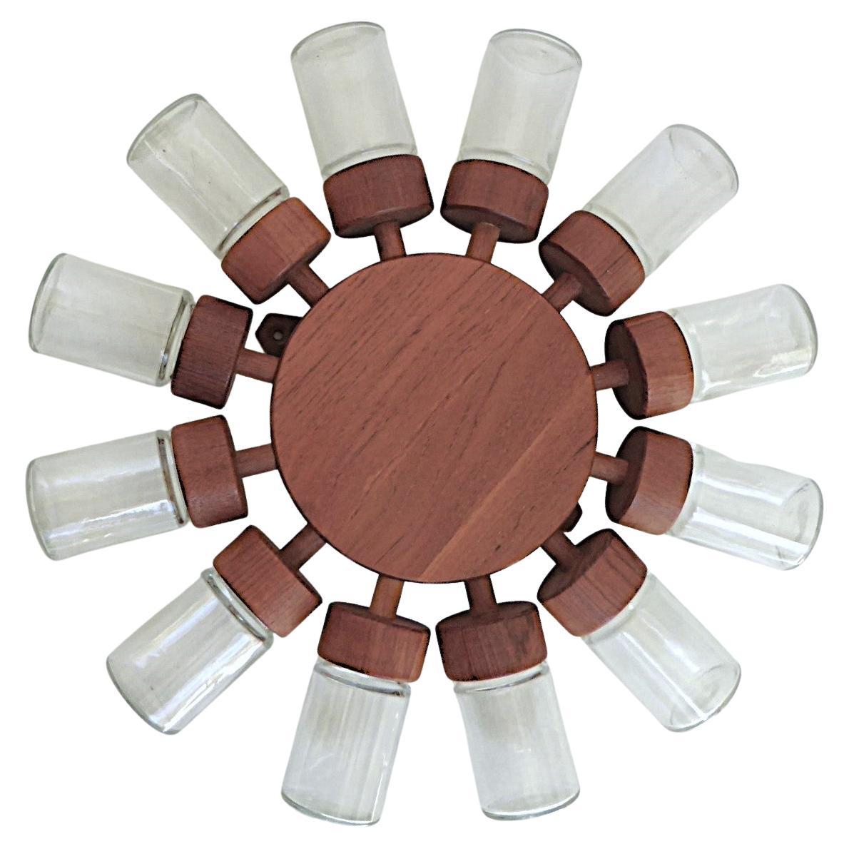 Convinienente y atractivo especiero giratorio de pared, de madera de teca, con 12 tarros de cristal, diseñado por Digsmed, Dinamarca, en 1964.  La placa trasera de teca se fija a la pared, los tarros se atornillan a los receptáculos de teca.  La