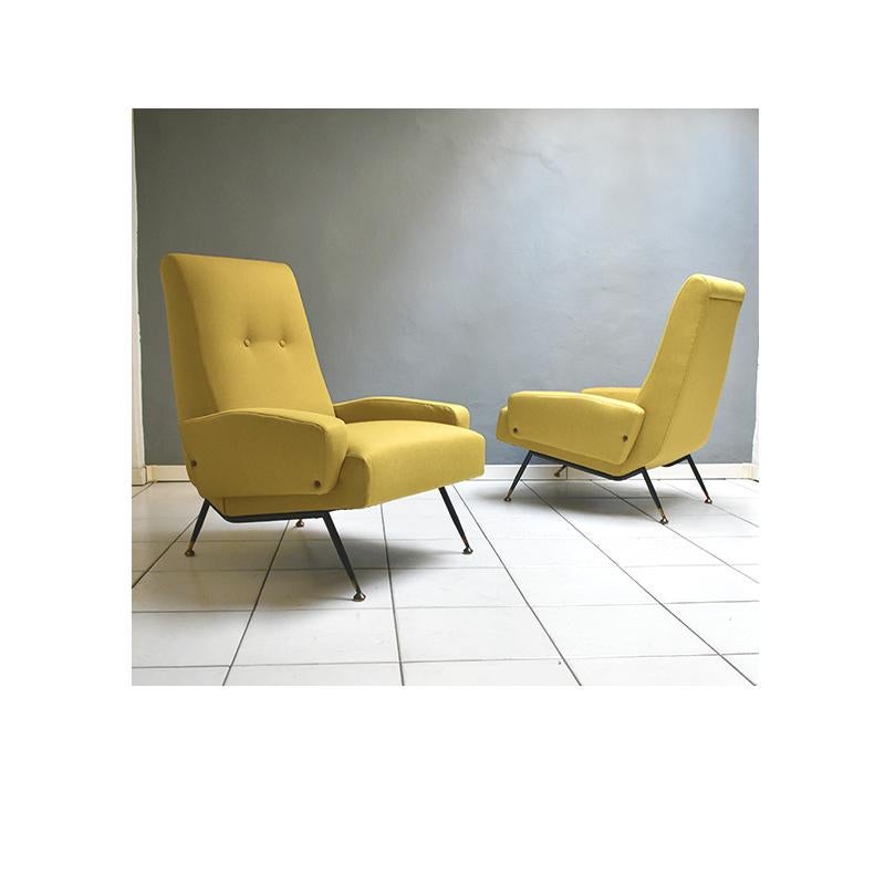 Set of two vintage sixties armchairs, Italian manufacture. 
The armchairs have a black iron legs and brass feet with an ocher fabric upholstery.
The upholstery of the armchairs is new.
 