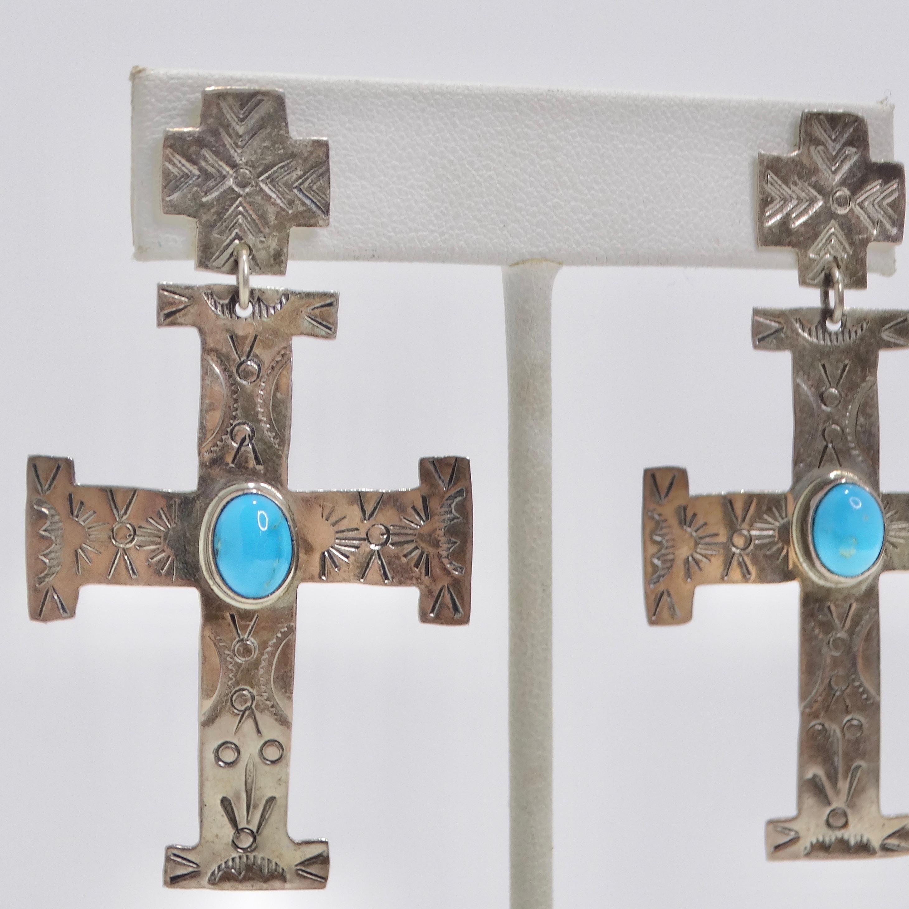 Experience the allure of the past with these 1960s Vintage Silver Turquoise Cross Earrings. These stunning silver dangle earrings boast a timeless cross motif, accentuated by captivating turquoise stone details and intricate geometric engravings. A