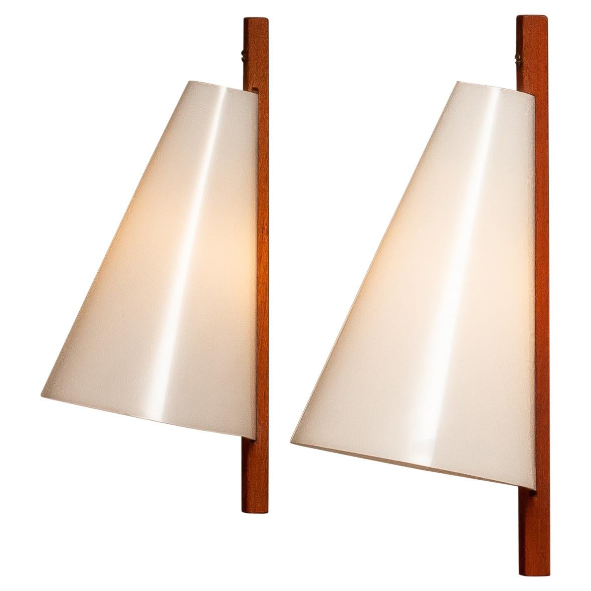 Original 1960's wall lights / scones designed by Uno & Östen Kristiansson for LUXUS, Vittsjö in Sweden. The wall lights are made of acryl plastic shade in white and a wall fixation in teak. Technically 100% and both wall lights have a screw fitting