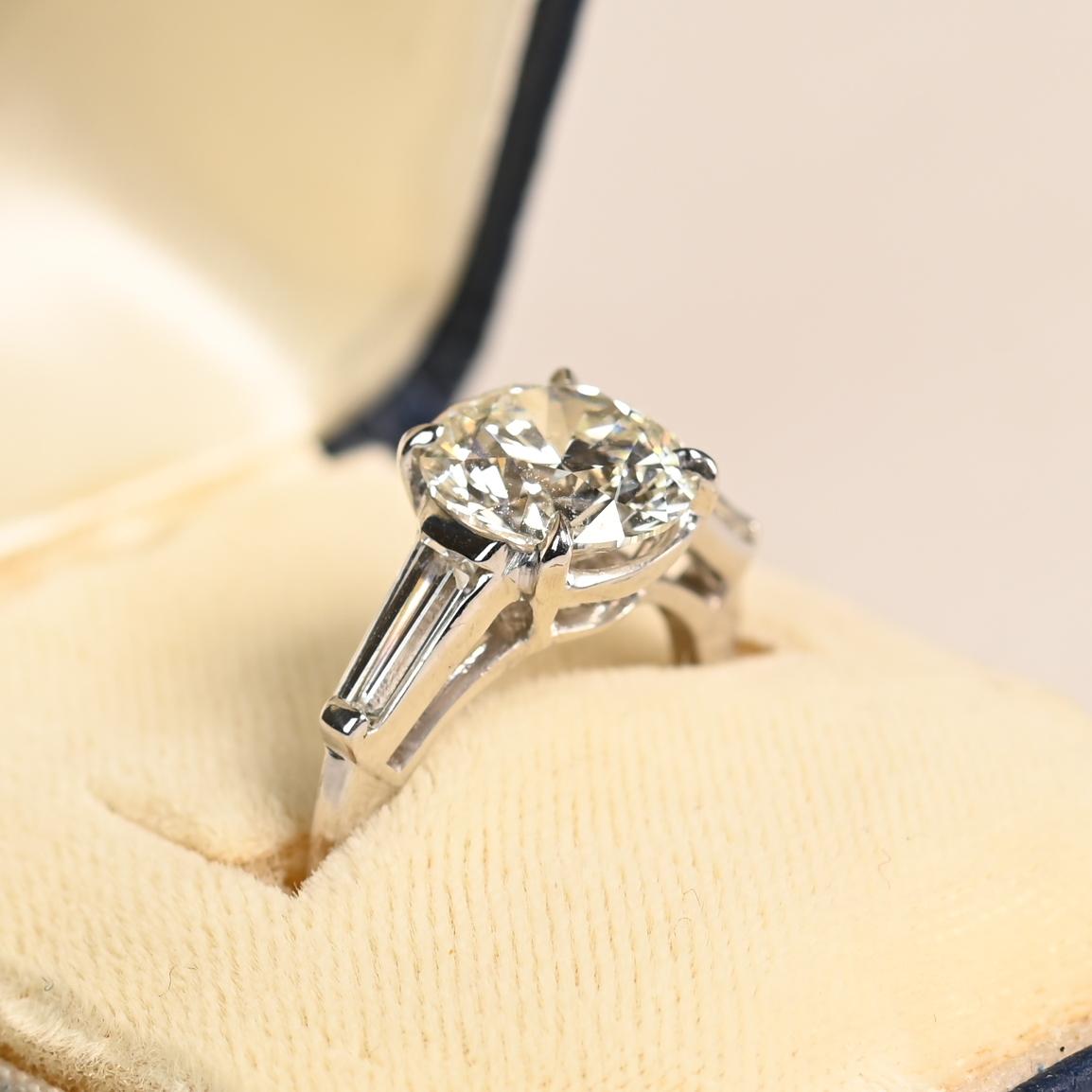 This exquisite vintage engagement ring, crafted in platinum circa 1960, features a stunning GIA-certified round brilliant-cut diamond at its center. Weighing approximately 3.00 carats, the center stone is graded I in color and SI2 in clarity,