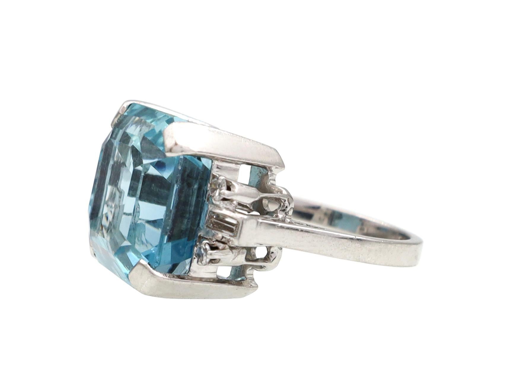 Vintage 10ct aquamarine and diamond cocktail ring in 18kt white gold. Set with an estimated 10.00ct octagonal step cut aquamarine in a raised four claw setting, flanked to either side with four round brilliant cut diamonds in claw settings and two