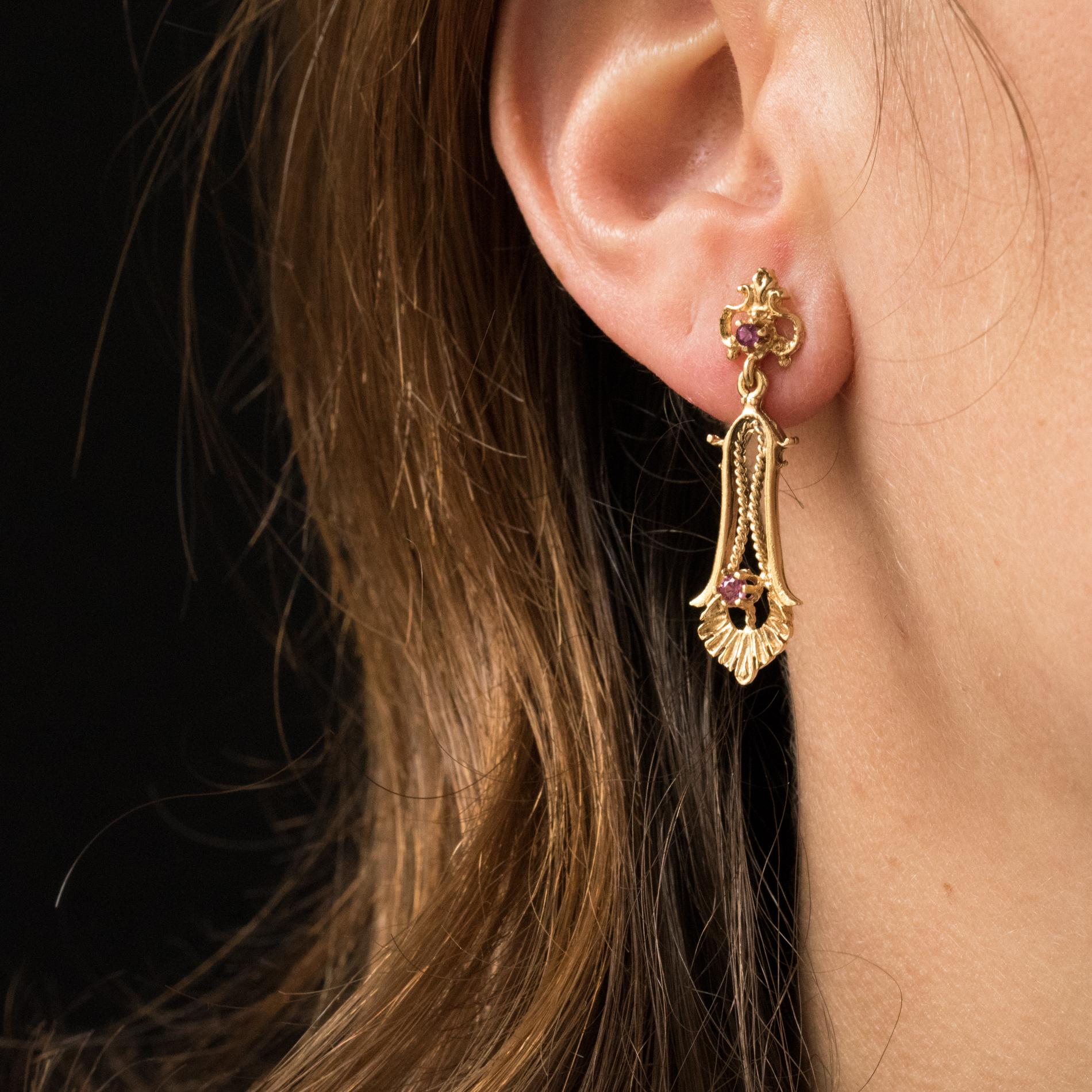 Earrings in 14 karats yellow gold.
Pretty dangle earrings, they are made of a perforated pattern set in the center of a small pink stone that holds in pendent an elongated pattern, chiseled and openwork with a gold cord. Another small pink stone is