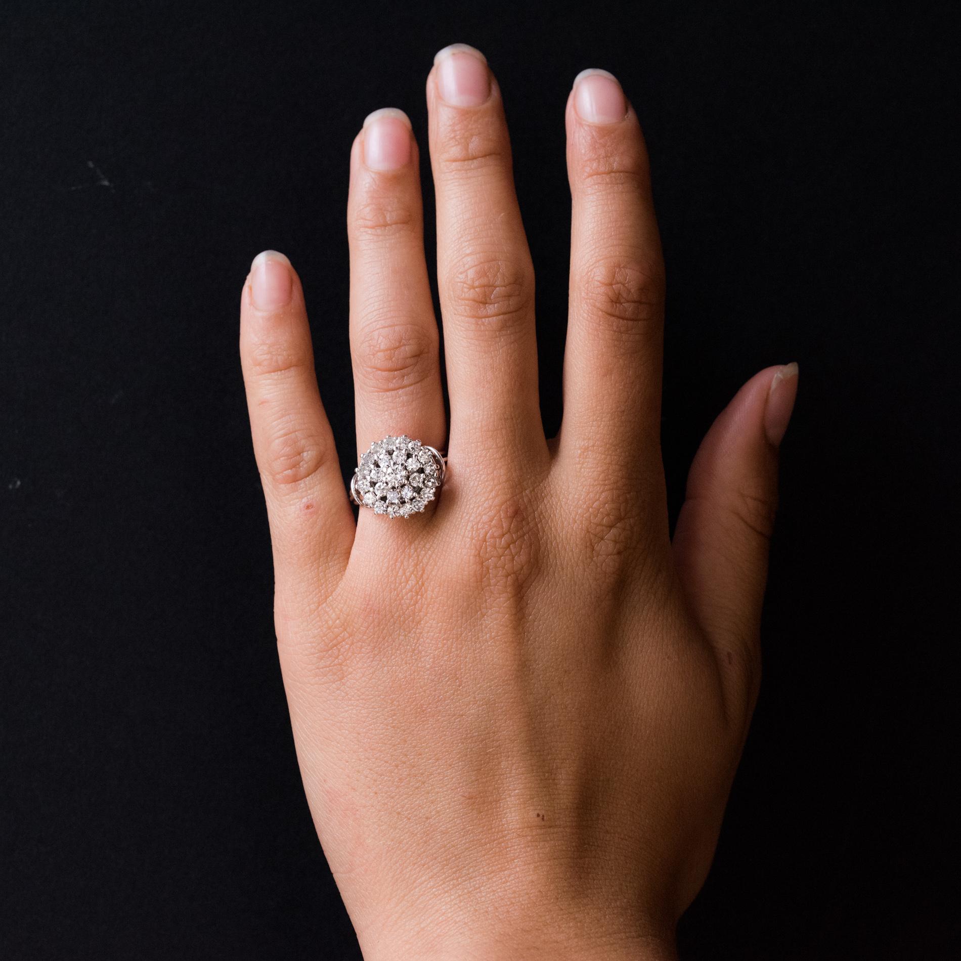 Ring in 18 karat white gold.
Round shaped, this retro ring is claw-set on its top with a modern brilliant-cut diamond, in a double entourage of modern brilliant-cut diamonds.
The basket is made of gold threads, the ring is also made up of 3 gold