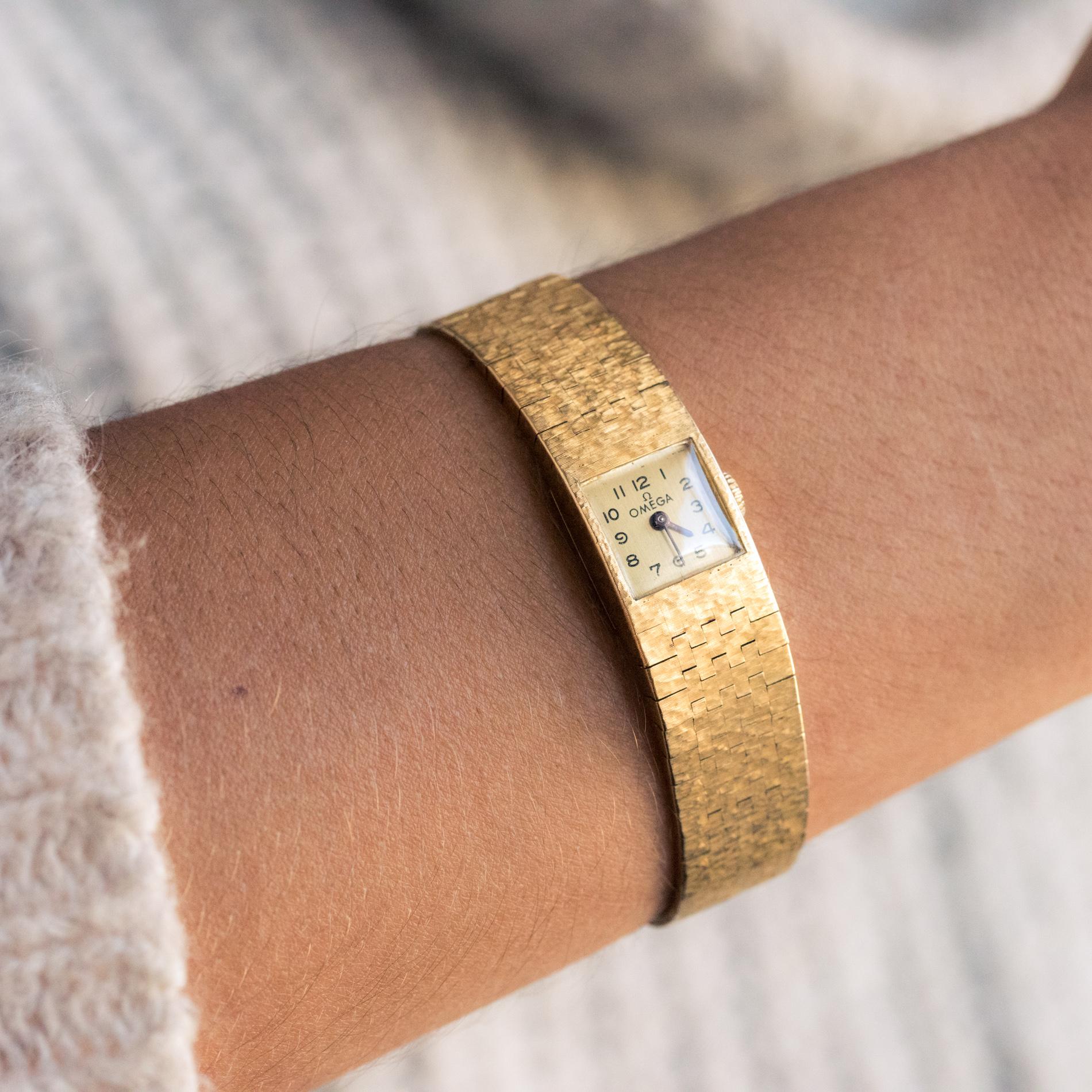 Damenarmbanduhr aus 18 Karat Gelbgold. 
Quadratisches Zifferblatt:: gebürsteter Boden mit arabischen Ziffern und schwarzen Emaillezeigern. 
Amati Stoff Mesh-Armband und artikuliert im Herbst. 
Leiterschließe mit Sicherheit. 
Mechanisches Uhrwerk.
