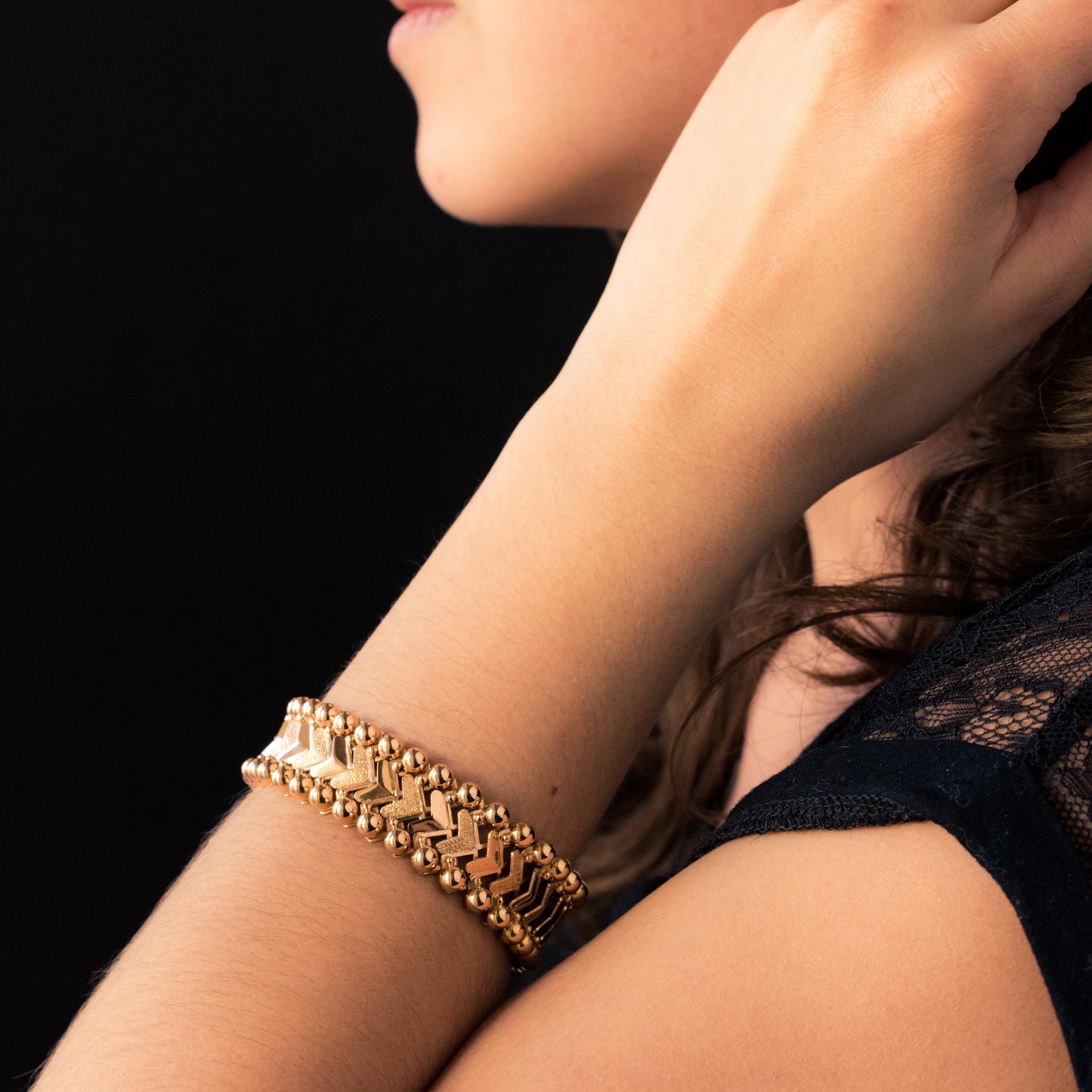Bracelet in 18 karat yellow gold.
Original, this retro bracelet is made up of alternating smooth and chiseled arrowhead patterns, and articulated between them. They are bordered on either side with gold pearls. The clasp is ratchet with safety