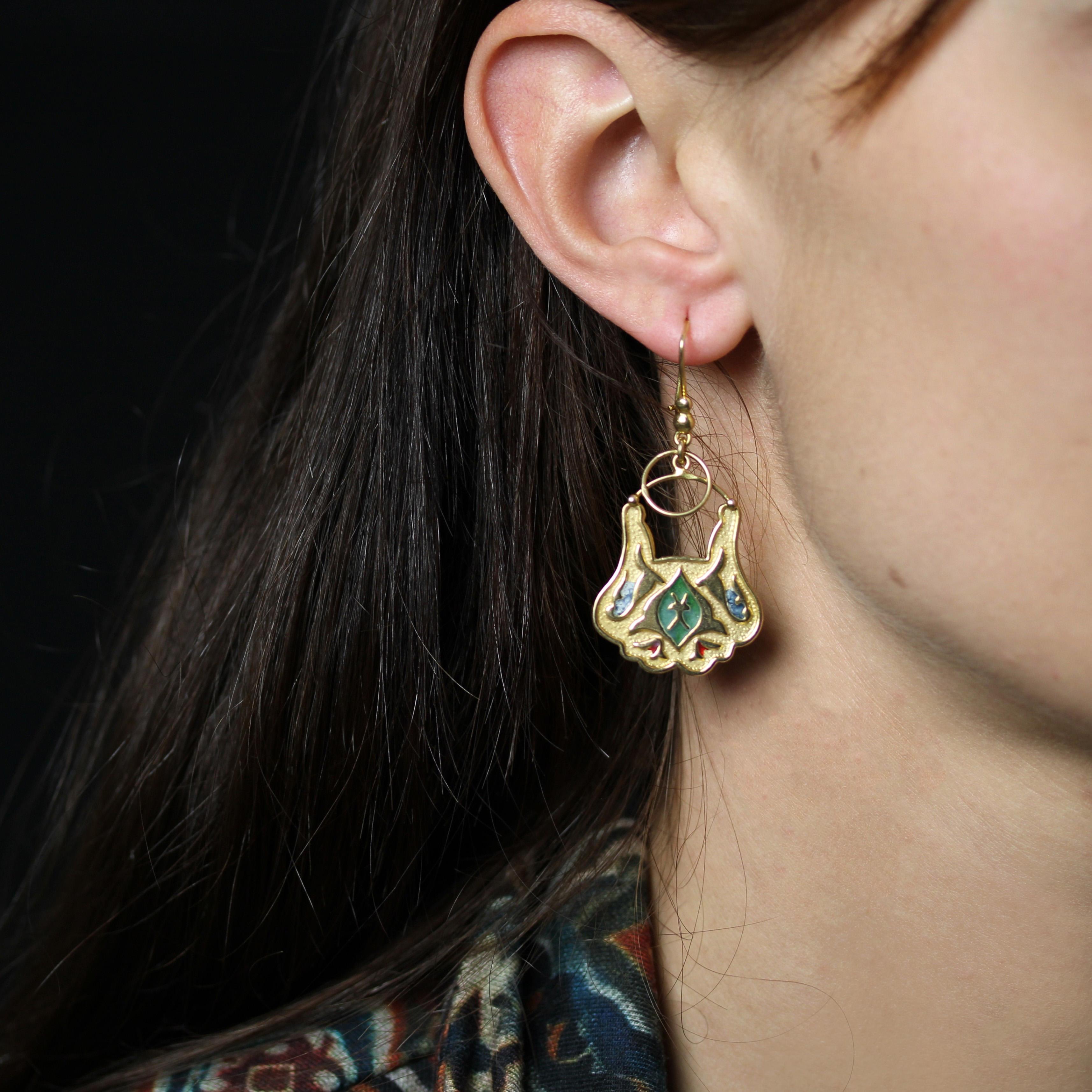 Pour les oreilles percées.
Boucles d'oreilles en or jaune 18 carats.
Paire de boucles d'oreilles ethniques, composées de deux perles d'or à la base et d'une plaque d'or gravée de motifs et partiellement émaillée de vert, de rouge et de bleu, ainsi