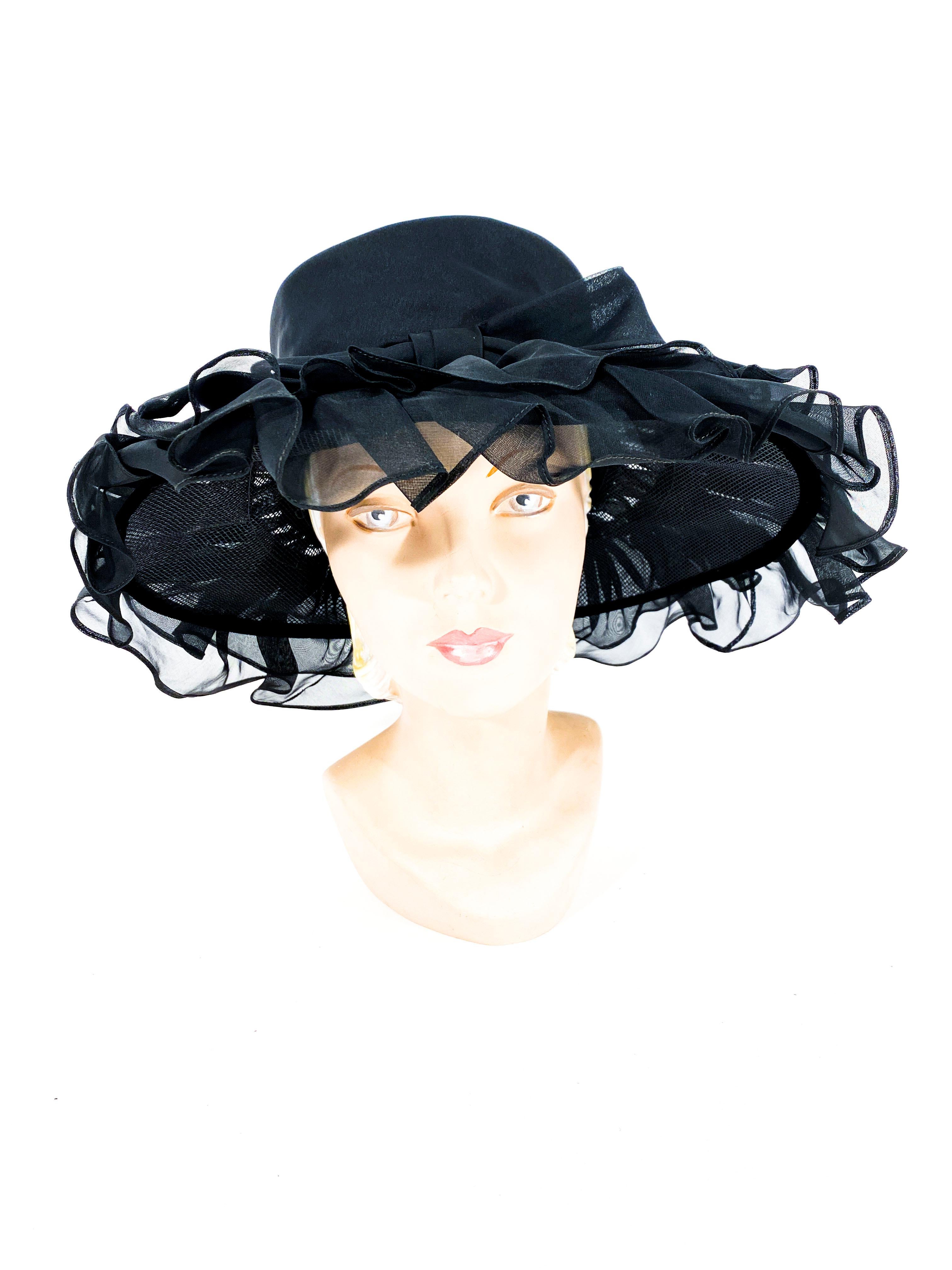Late 1960s to early 1970s black wide brimmed hat decorated with a double row of organza ruffles, a tall crown, and an oversized bow centered on the band.