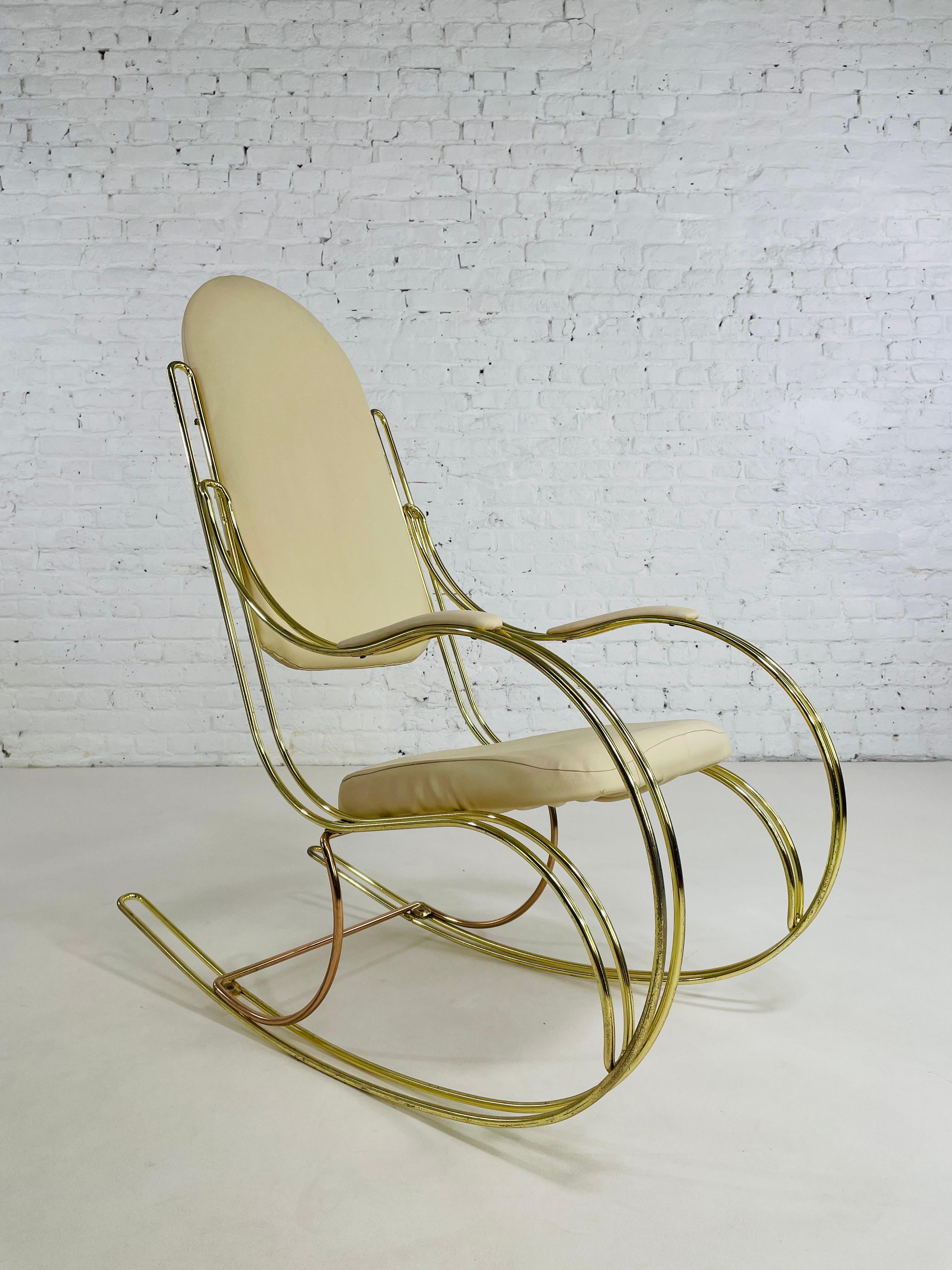 1960s - 1970s Brass And Beige faux leather rocking chair composed of a brass rounded and curved brass structure adorned with beige skaï back and seat.