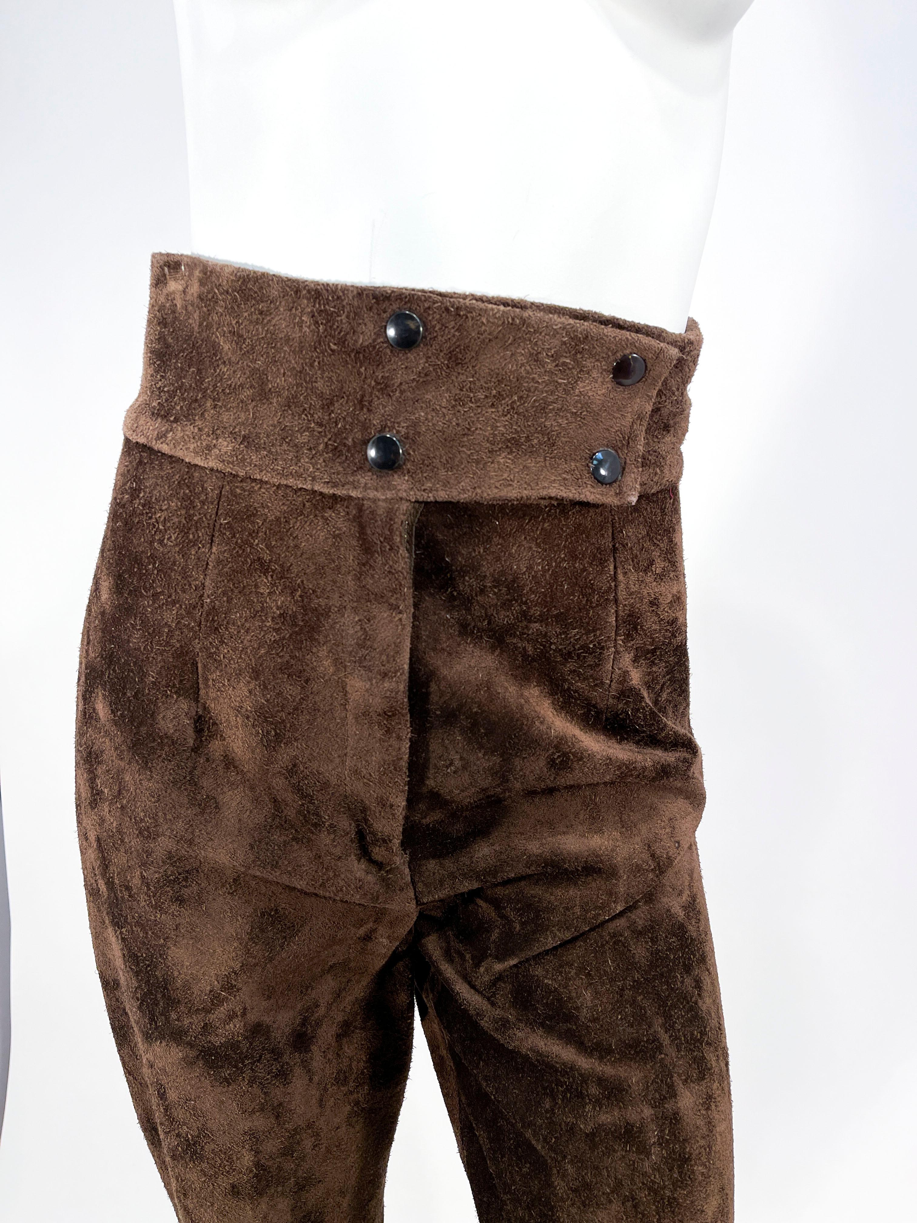 Late 1960s to early 1970s Saks Fifth Ave. chocolate brown brushed suede pants with a wide high wide waistband and a double snap closure. The legs have permanently stitched pleats and have a slight flair. These are unlined with a zipper fly.