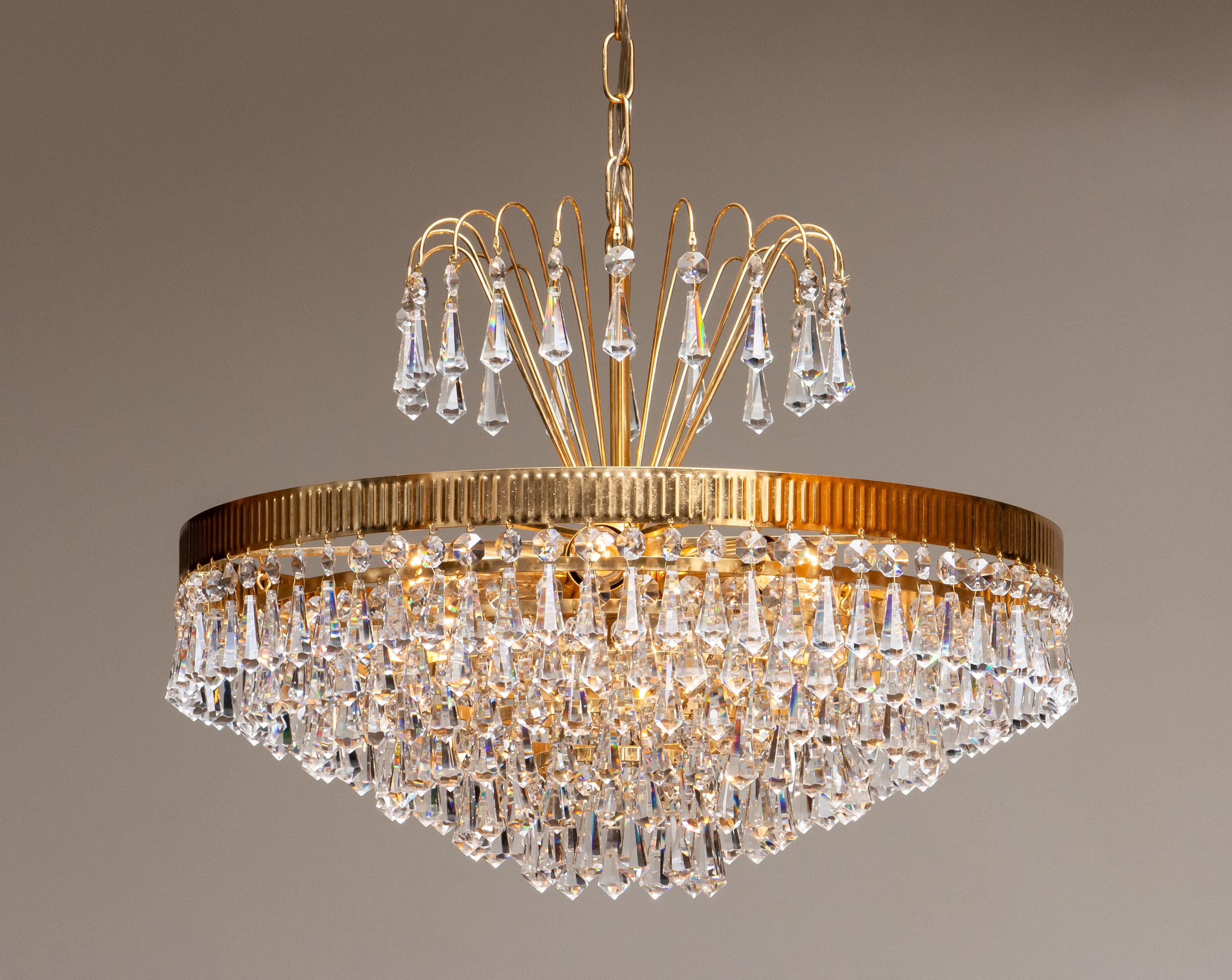 Äußerst schöner und seltener 24-karätiger vergoldeter Kronleuchter der Rejmyre Armaturfabrik Rejmyre, Schweden, 1960er Jahre.
Der Kronleuchter besteht aus sechs Ringen und einer Krone, die mit facettierten Kristallketten gefüllt ist. Der