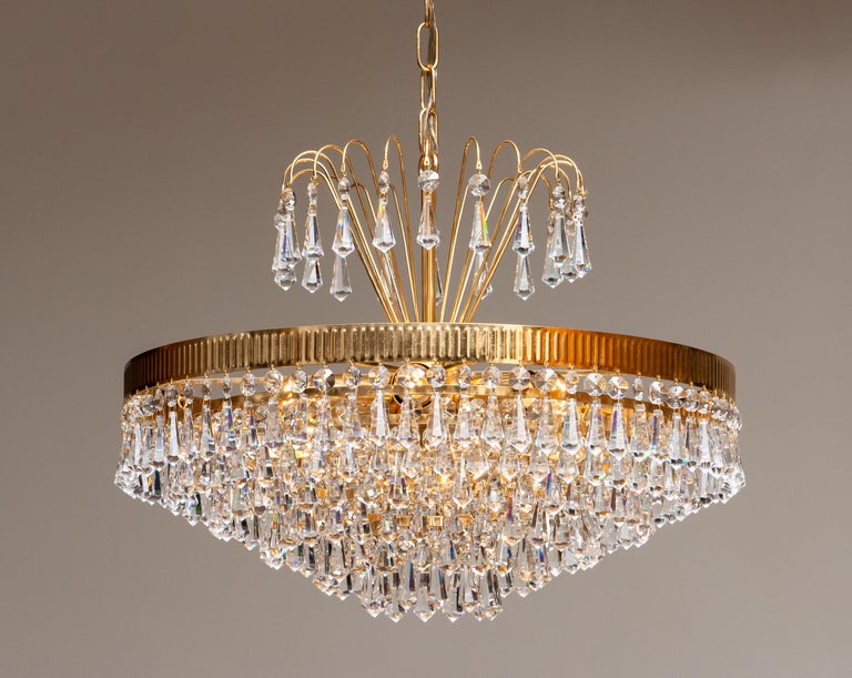 Extremely beautiful and rare 24-carat gold-plated chandelier made by Rejmyre Armaturfabrik Rejmyre, Sweden, 1960s.
The chandelier is build up out of six rings and a crown filled with faceted crystal chains, total diameter of the fixture is 40cm or