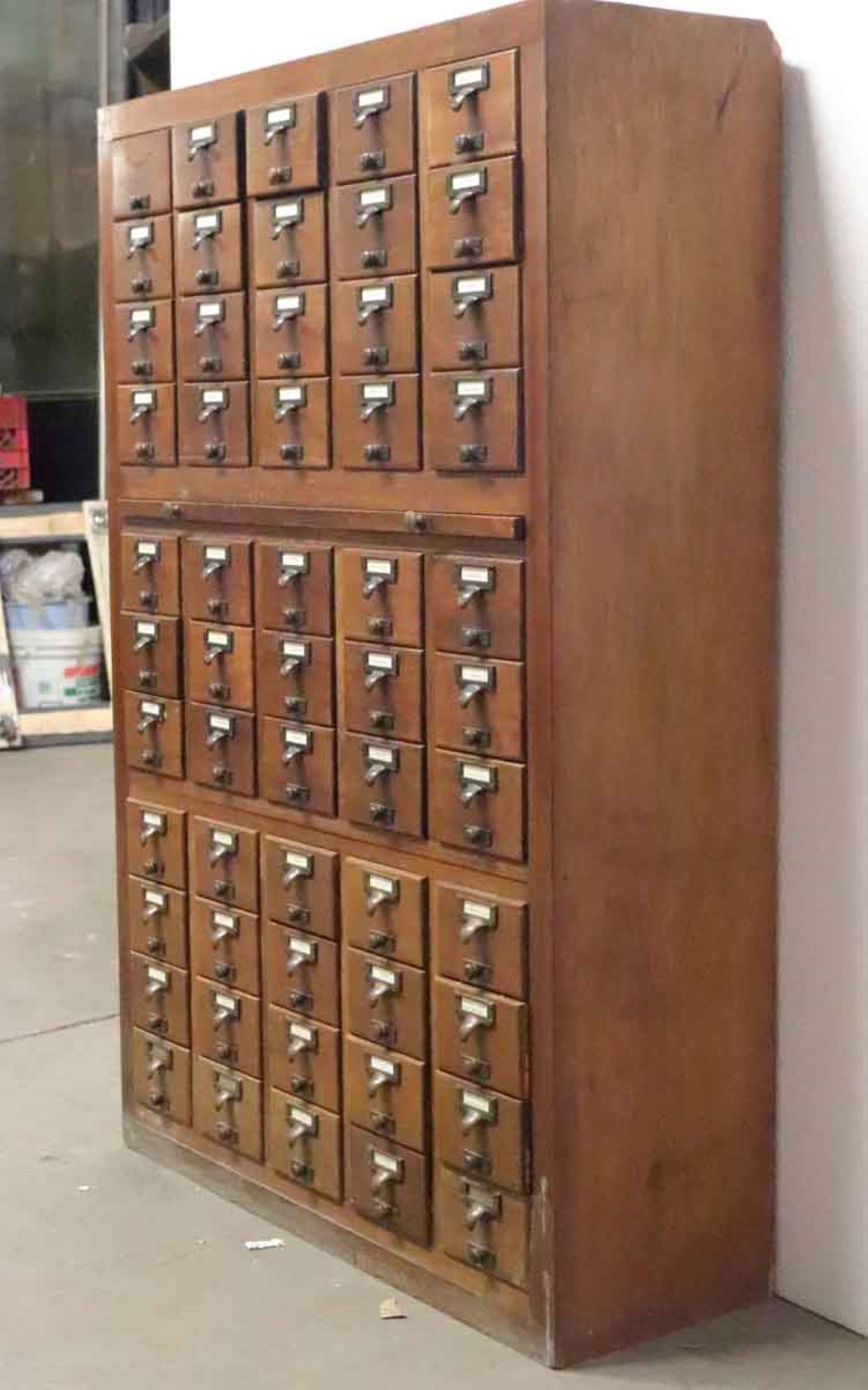 1960s library card catalog cabinet with 55 drawers and brass hardware. One pull missing. Some damage to back right corner. This can be seen at our 400 Gilligan St location in Scranton, PA.