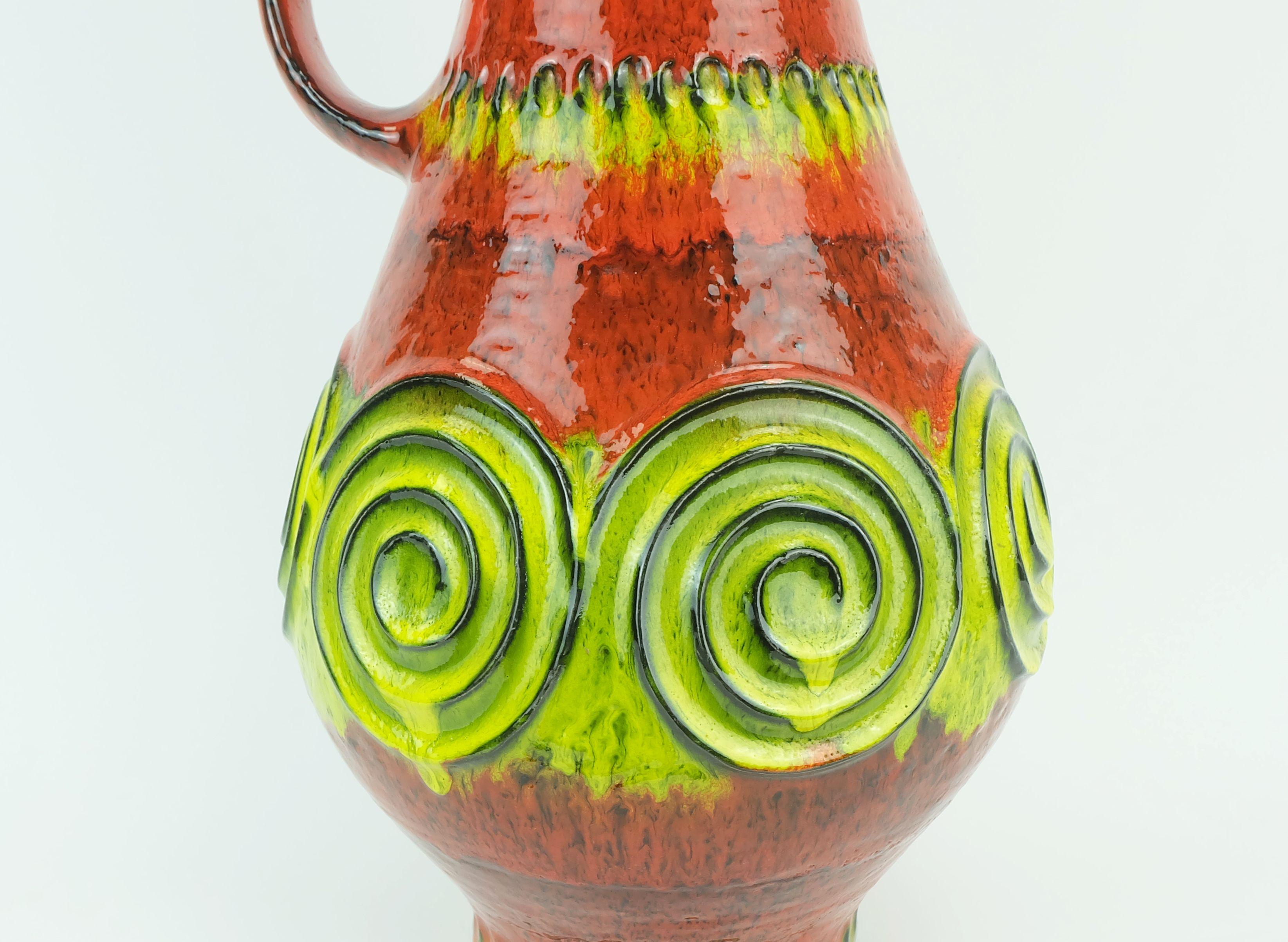 A fantastic vintage West German vase manufactured by Jasba Keramik in the 1960's to early 1970's. Model number N 322 13 45 with a colorful shiny glaze  in different shades of orange, lime green and yellow and some black combined with a squiggle