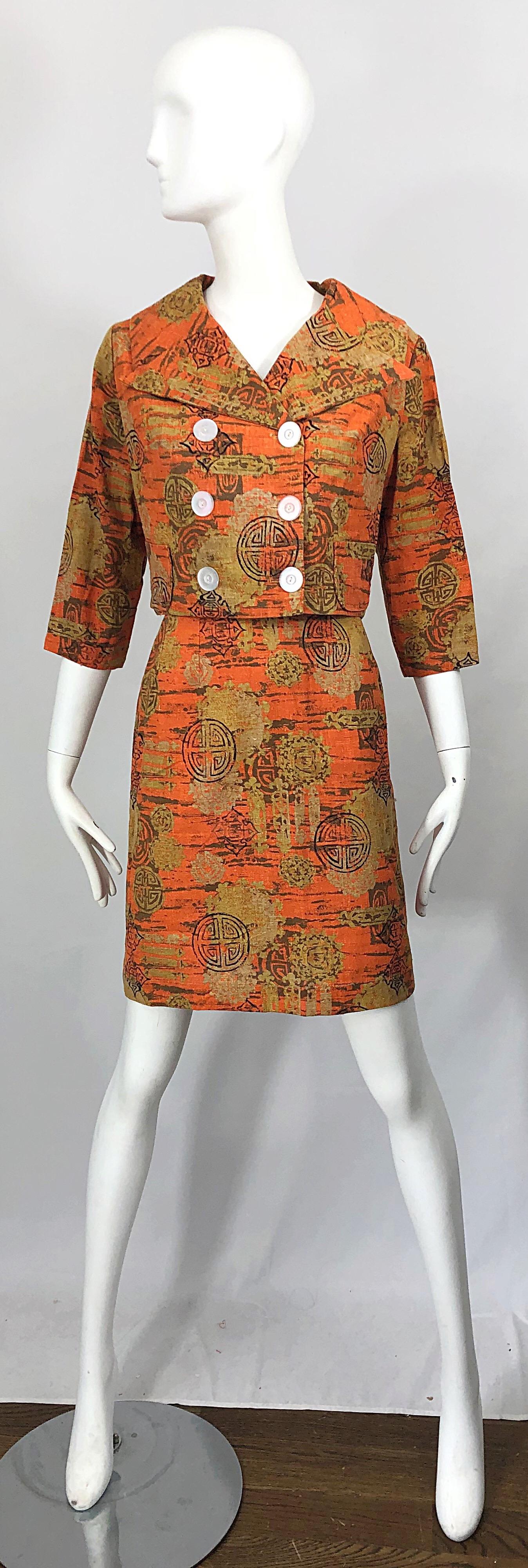 Chic 1960s abstract Asian batik print linen skirt suit! Features warm colors of burnt orange and tan throughout. Pillbox style jacket is double breasted, cropped and has 3/4 sleeves. Clear buttons and pockets at each side of the waist on the jacket.