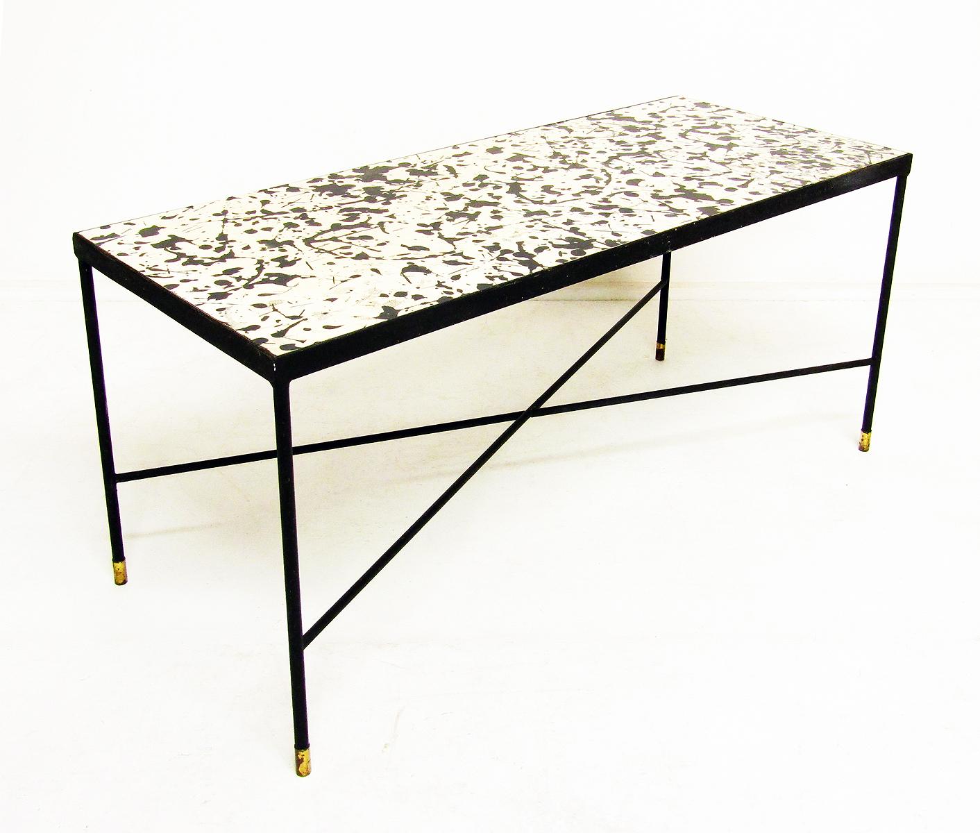 A vintage 1960s geometric designer coffee table in iron and formica with brass feet.

Reminiscent of Jackson Pollock's drip paintings, the formica surface is in good vintage condition.

It was very probably retailed by Heals in the 1960s.