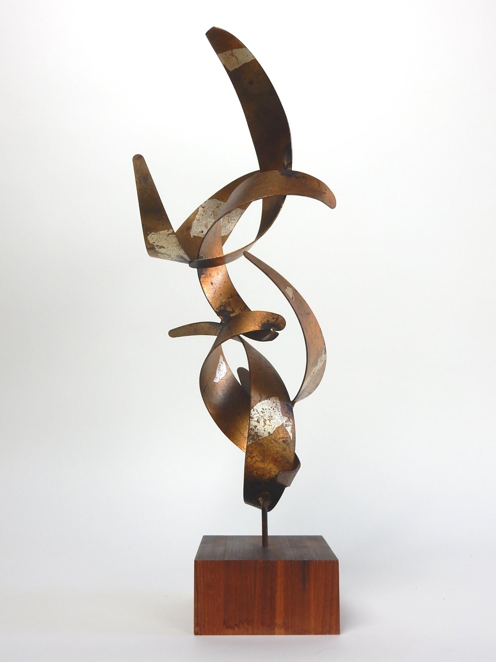 Rare early personal work of art by Bijan, (1936-2016).
Six perfectly contorted flame shapes welded together
and pierced into a teak block.
Signed on bottom edge (pictured).
Metal has a warm aged patina on top sides while
gold leaf with a splash
