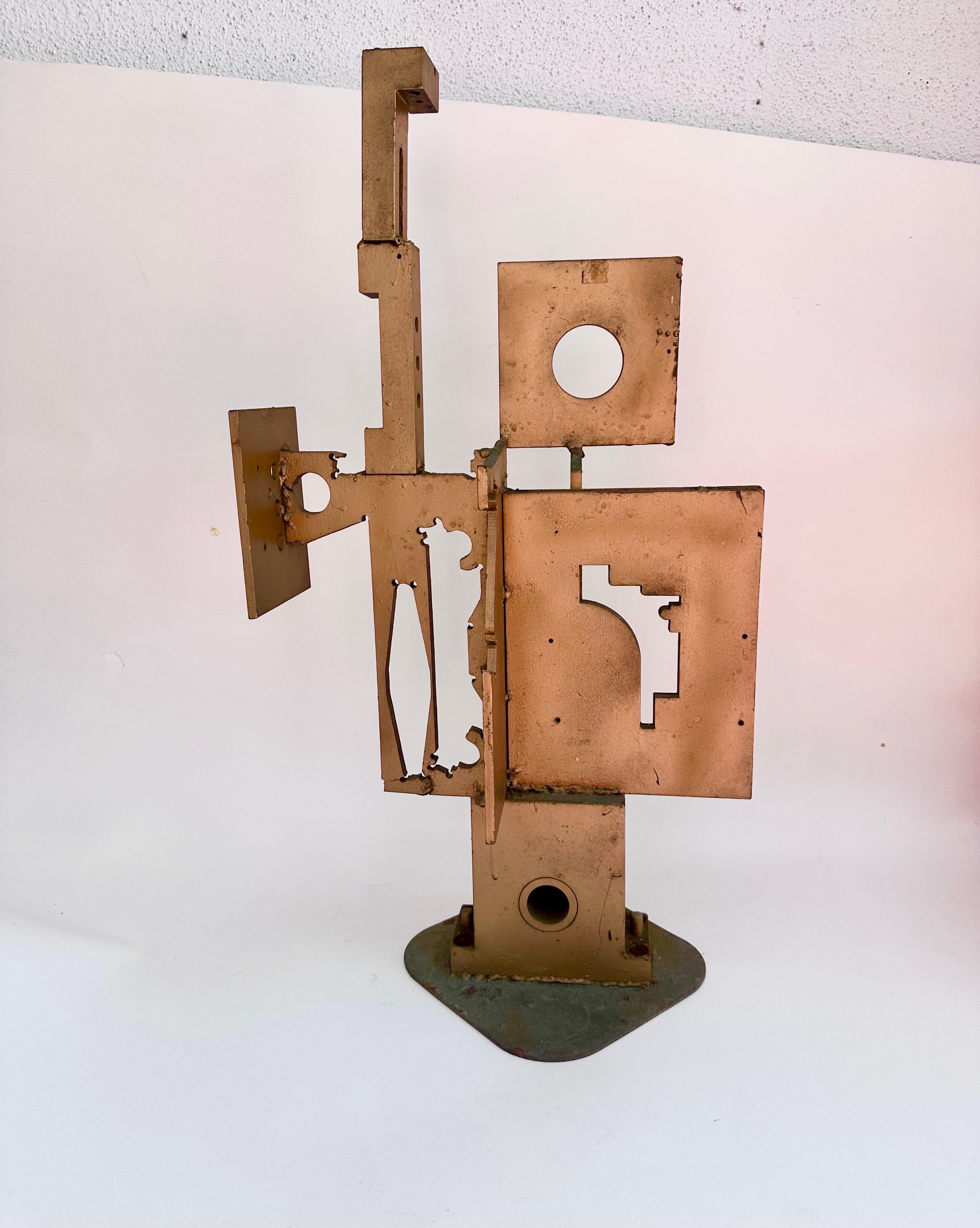 1960s Abstract Sculpture believed to be by Matthew Strumor is a medium-sized metal artwork from the Post-War period. This handmade sculpture features a geometric cubist design in the Brutalist style, painted a gold tone reflecting the industrial