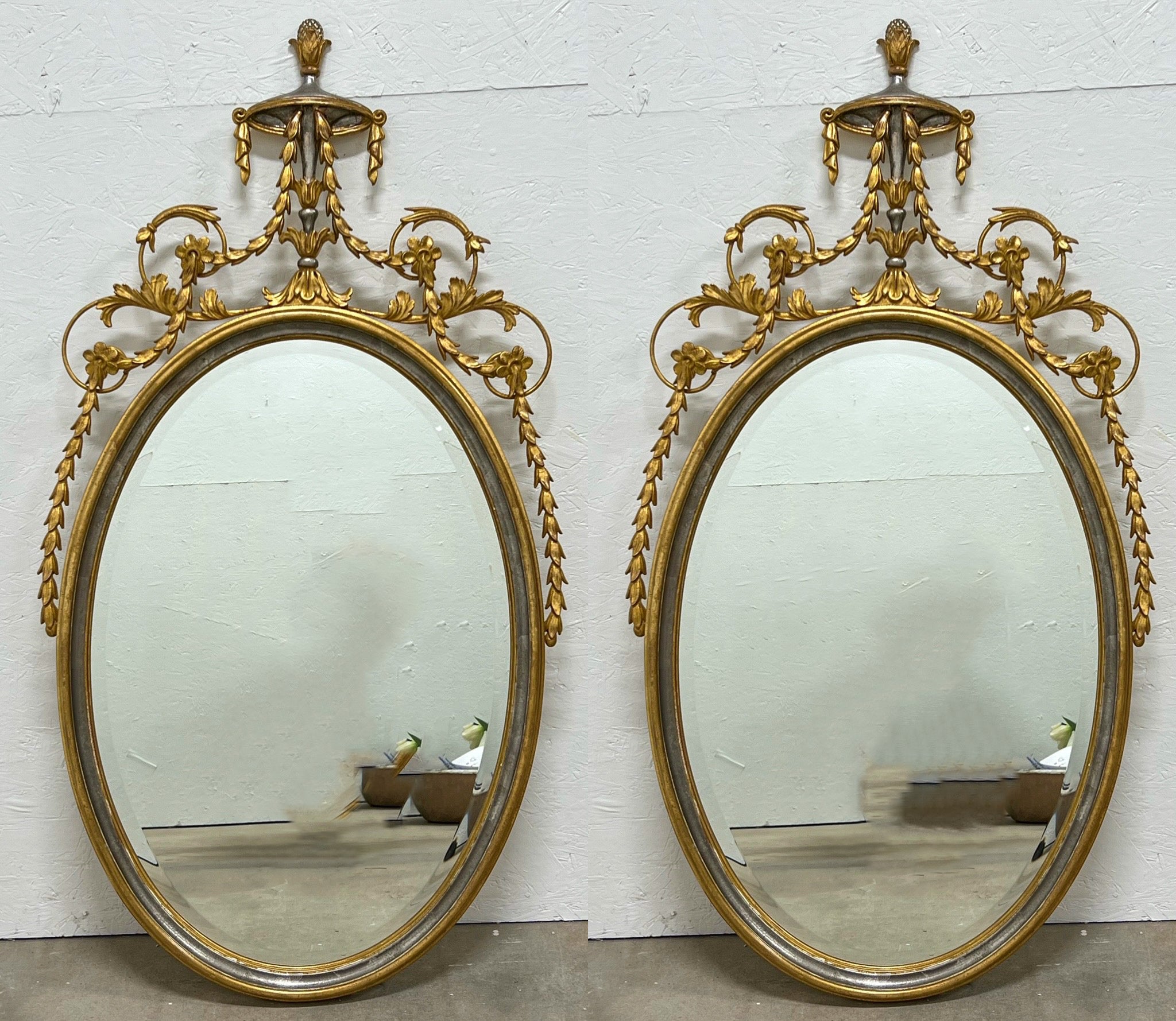 These are timeless! It is a pair of Adam Style silver and gold gilt carved Italian mirrors attributed to Friedman Brothers. They are in very good condition.