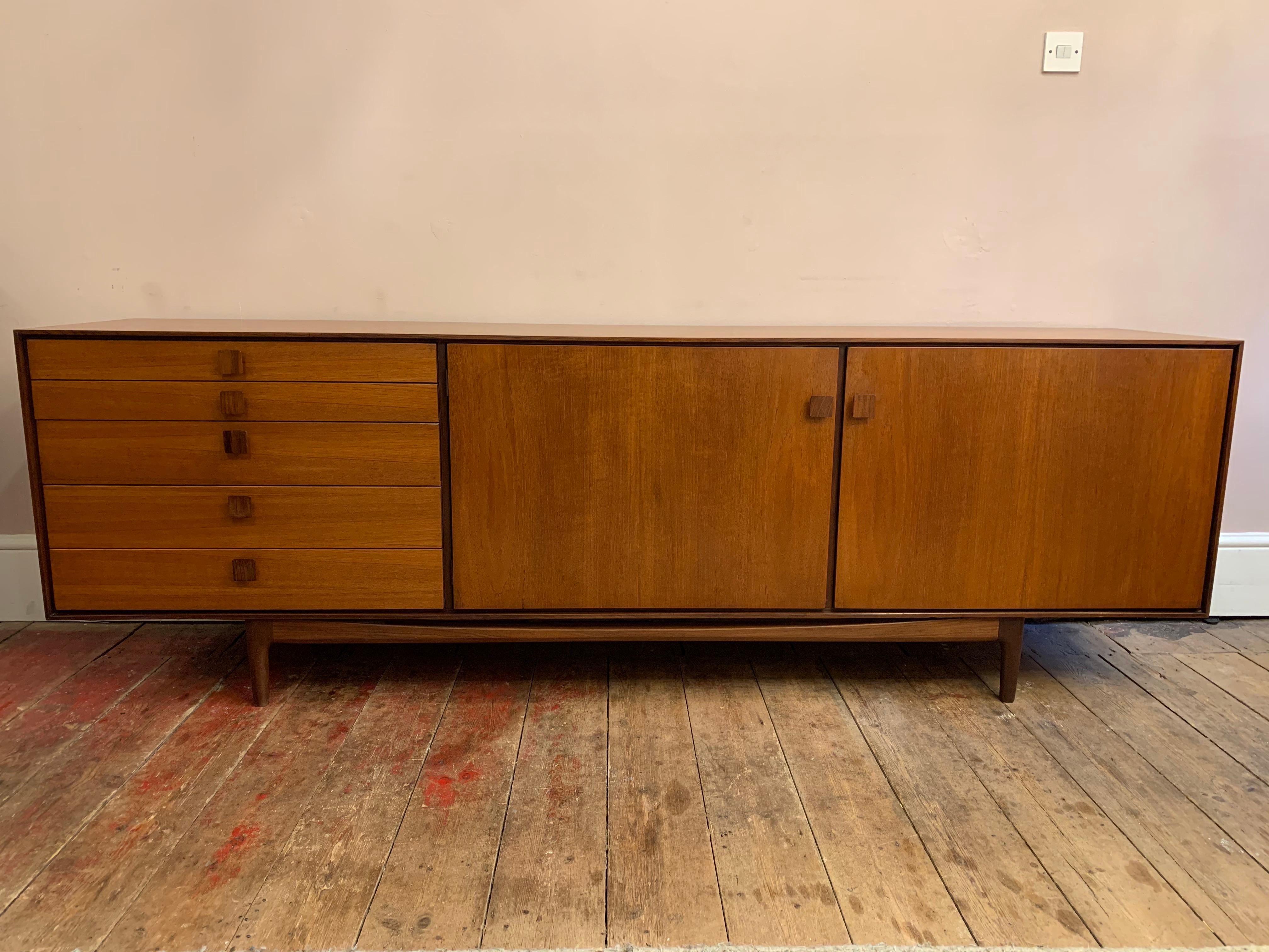 1960s G Plan sideboard designed by Ib Kofod-Larsen. This long sideboard is very well-made from Afromosia Teak. The sideboard has two doors and five drawers of different sizes with the top drawer covered inside with felt for cutlery which also has an