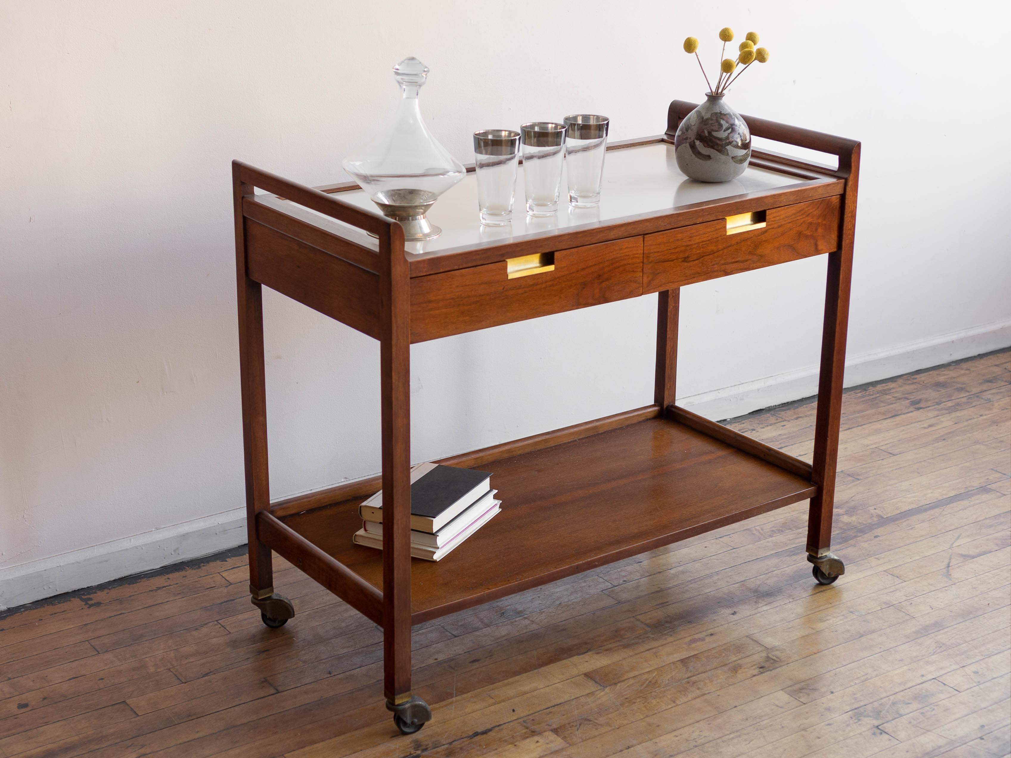38” x 18.75” x 33.5”H overall; top surface is 31”H, bottom shelf height is 17.75”H

This vintage walnut American of Martinsville Accord bar cart is a stunning piece of furniture that is both stylish and practical. Its black walnut veneer and ivory