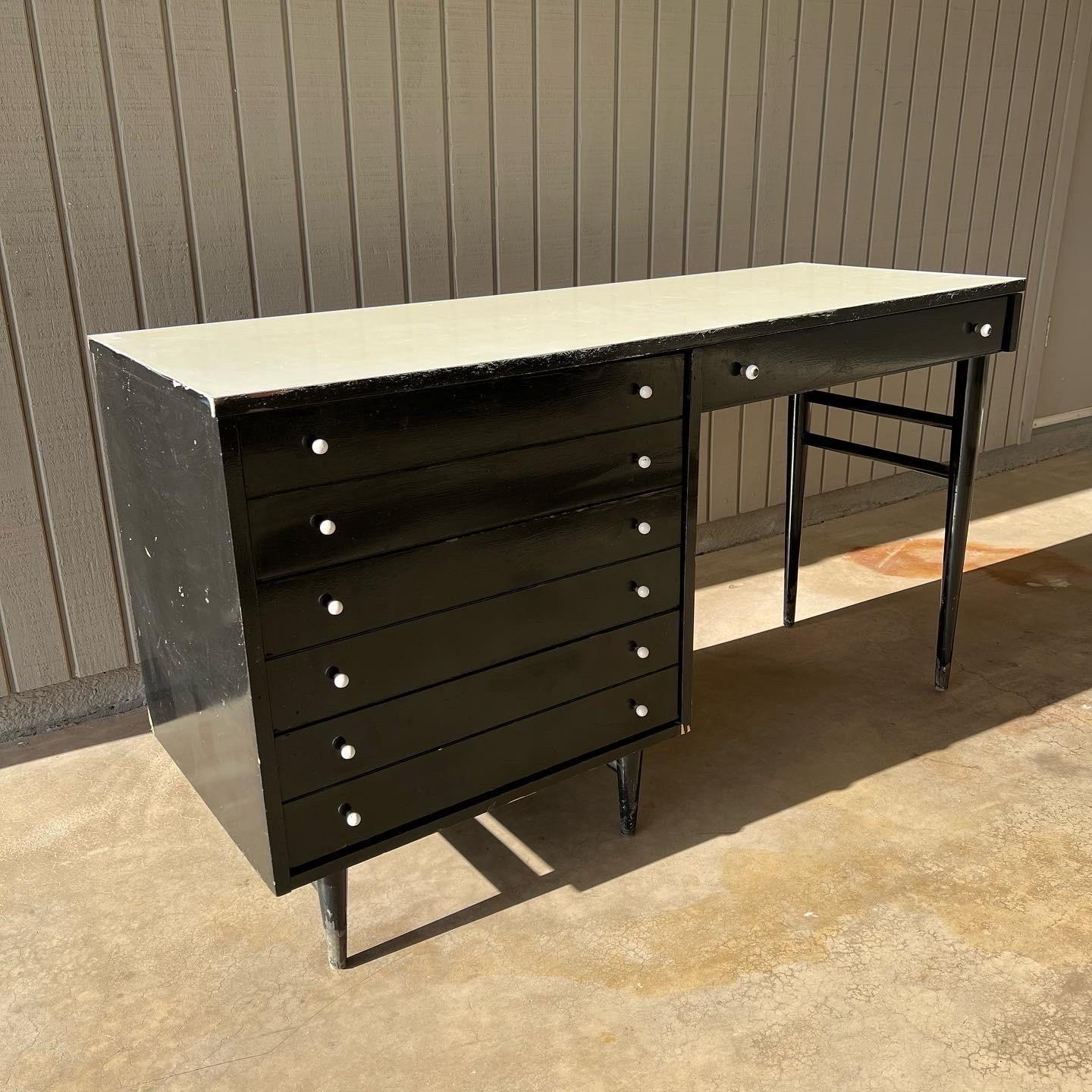 1960s American of Martinsville desk. This line came in black lacquer with white Formica tops, so the coloring is original. The top was repainted a bit sloppily at some point, so I’m not sure how the quality of the original top is underneath. Much of